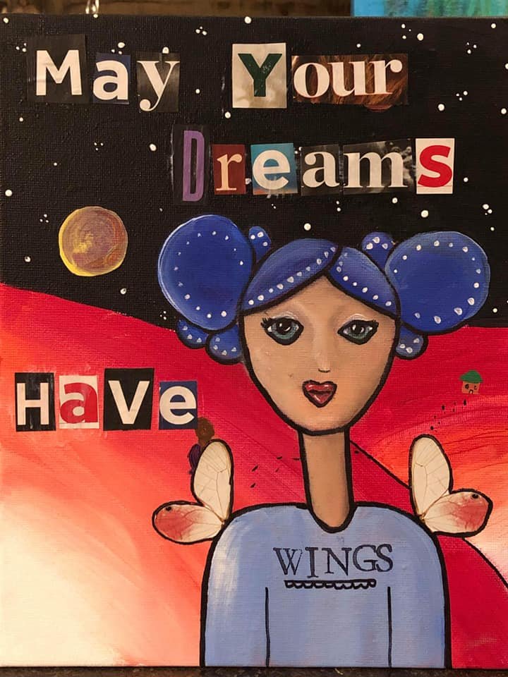 A colorful poster with the phrase 'May Your Dreams Have Wings.' It features a cartoon girl with blue hair styled in two buns, a serene expression, and angel wings on her back, set against a starry night sky and a red background.