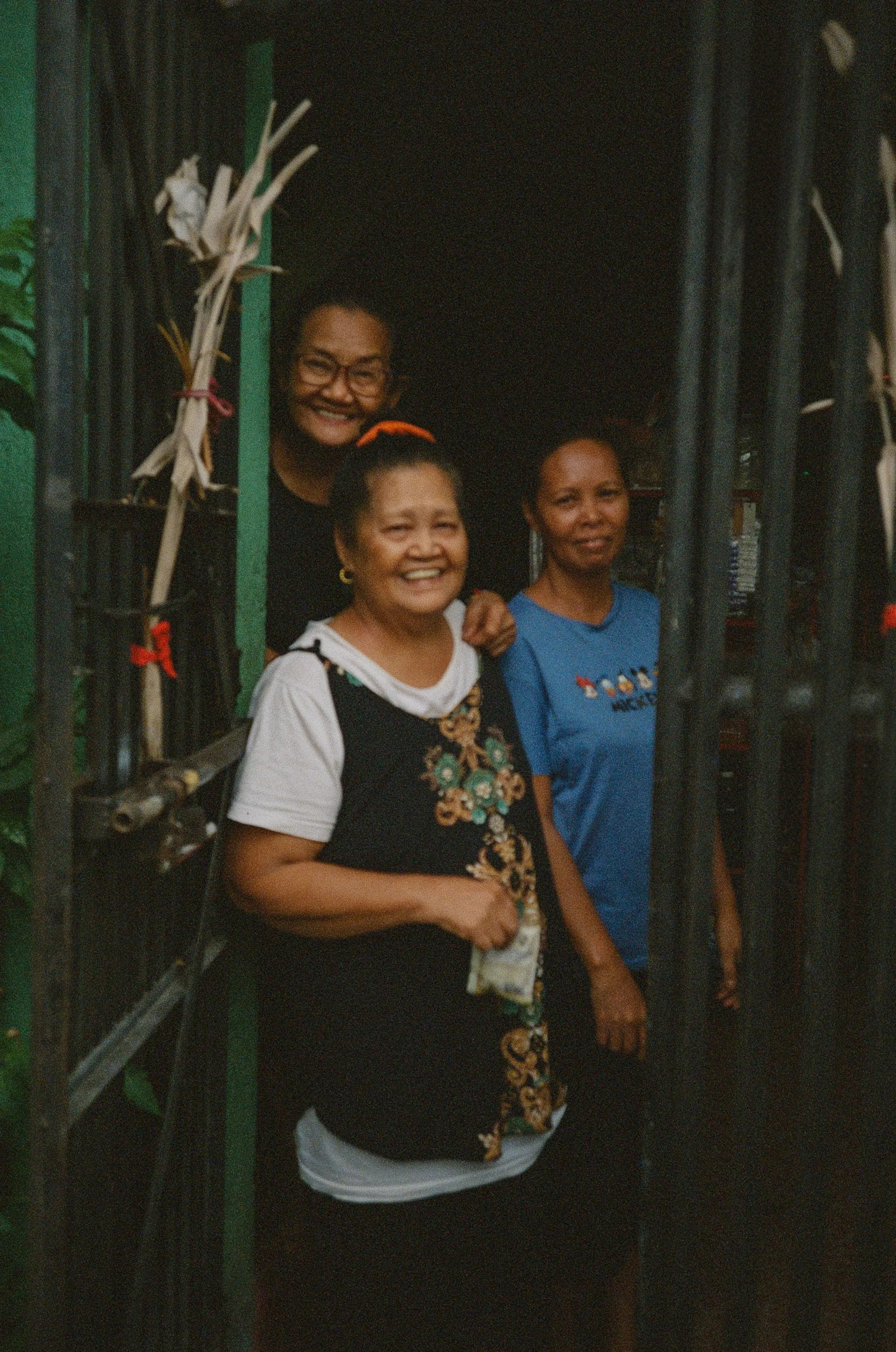 Three women smiling and standing at a doorway, with one woman on the outside and two women inside.