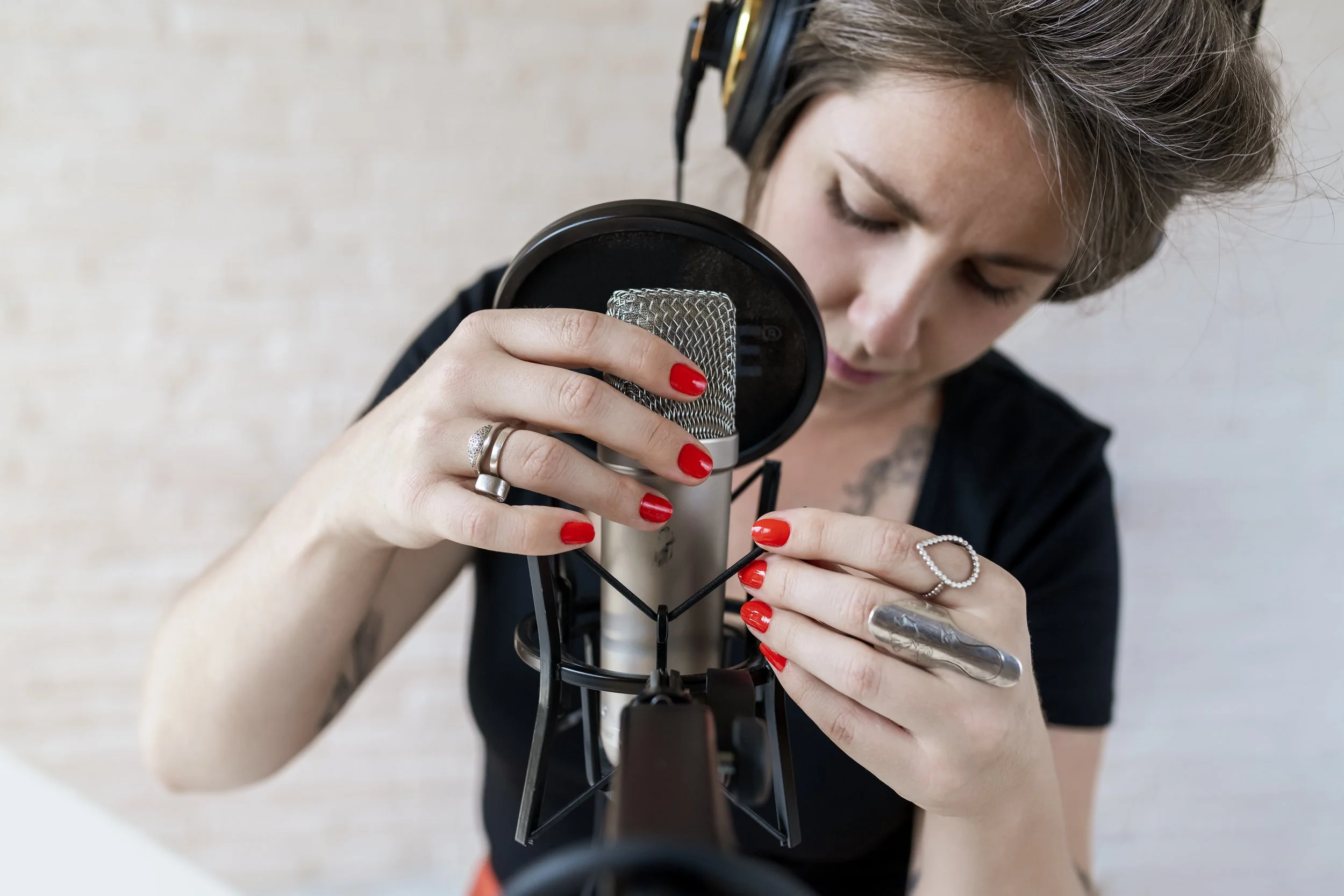 Sarah Rachel Brown wearing headphones and speaking into a microphone while working on a podcast.