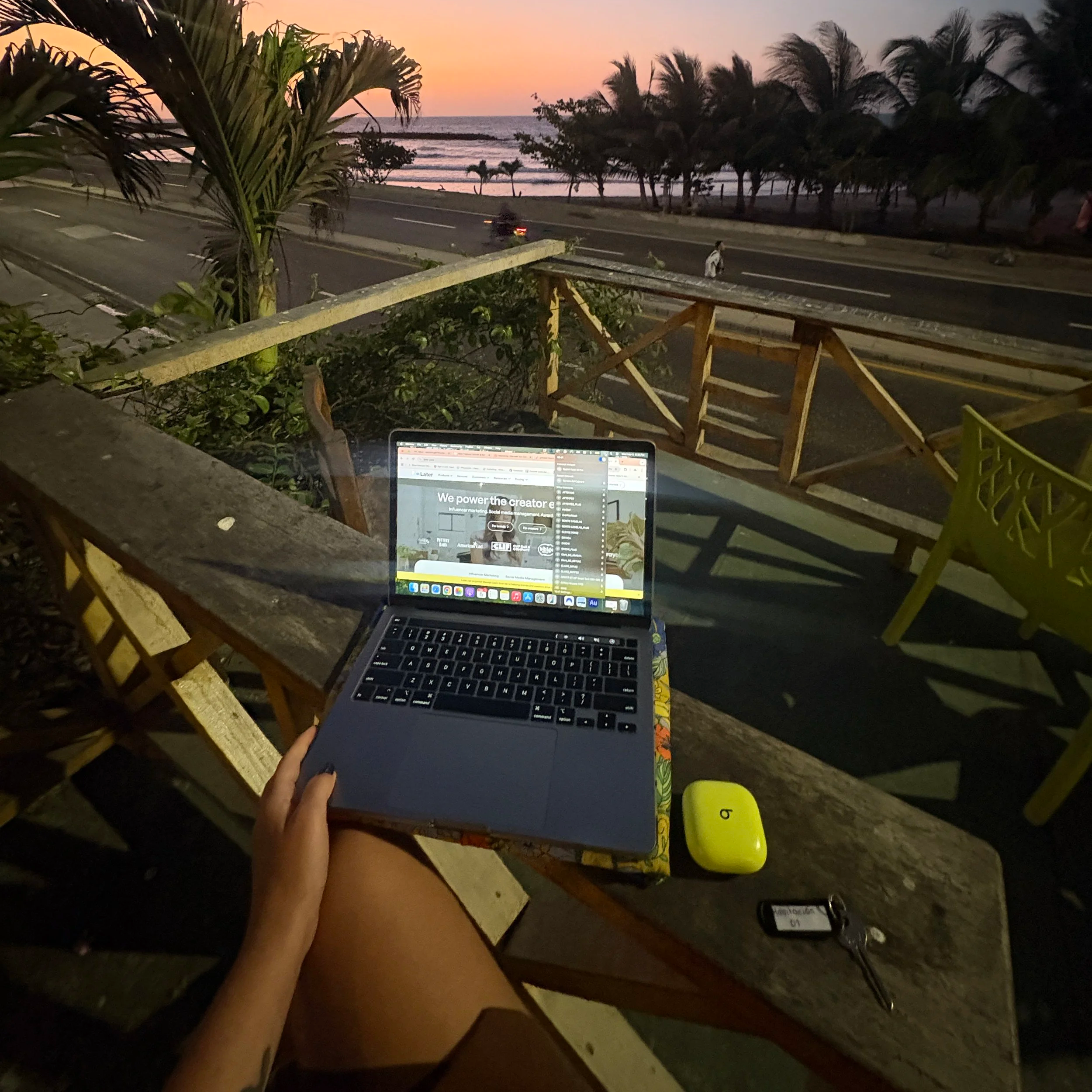 Sarah Rachel Brown working on her laptop as a digital marketer, with a beach view in the background, representing remote work and the flexibility of creative consulting.