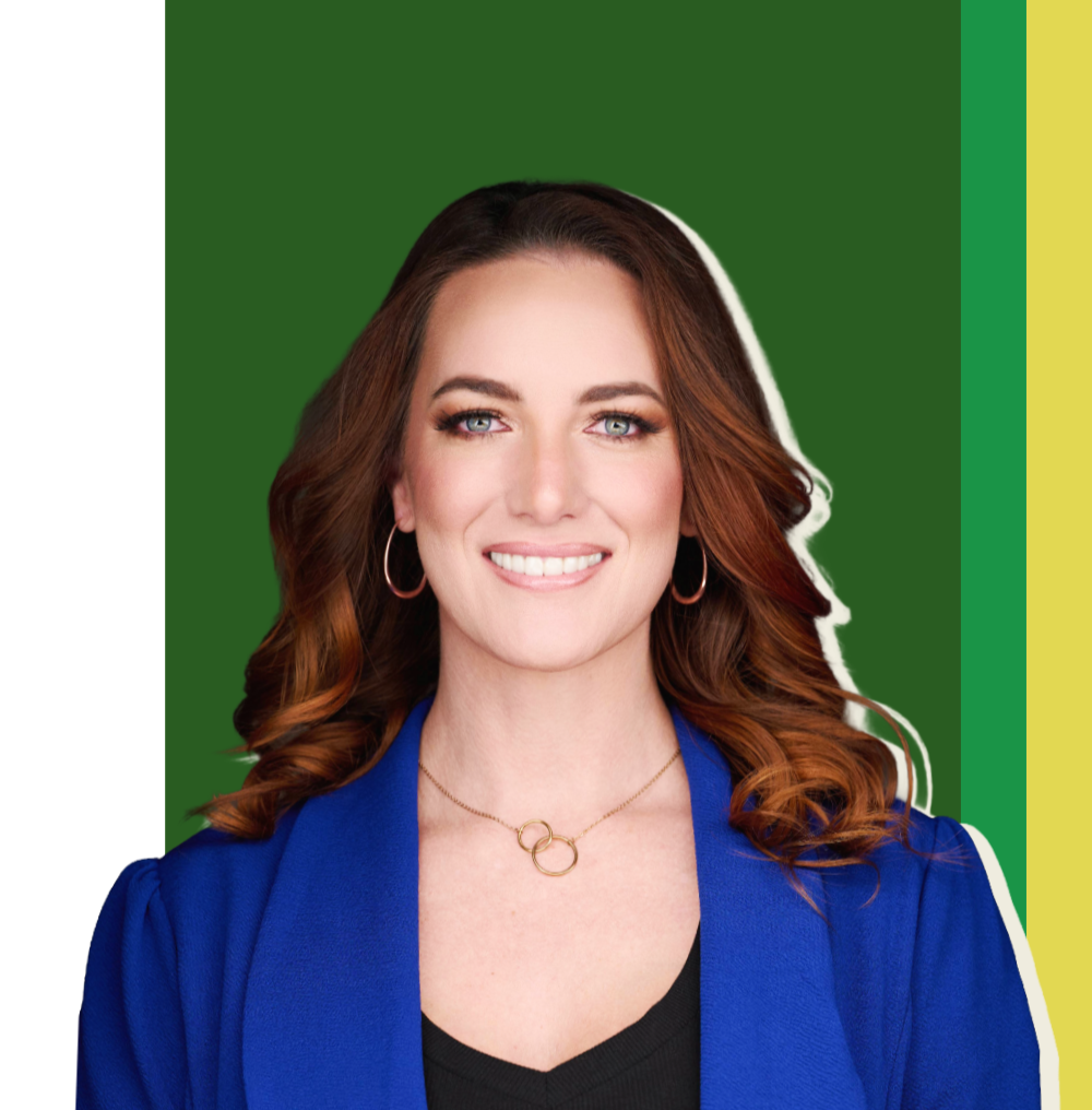 A woman with red hair, blue eyes, and earrings, wearing a blue blazer and a black top, smiling against a background with green, yellow, and black colors.