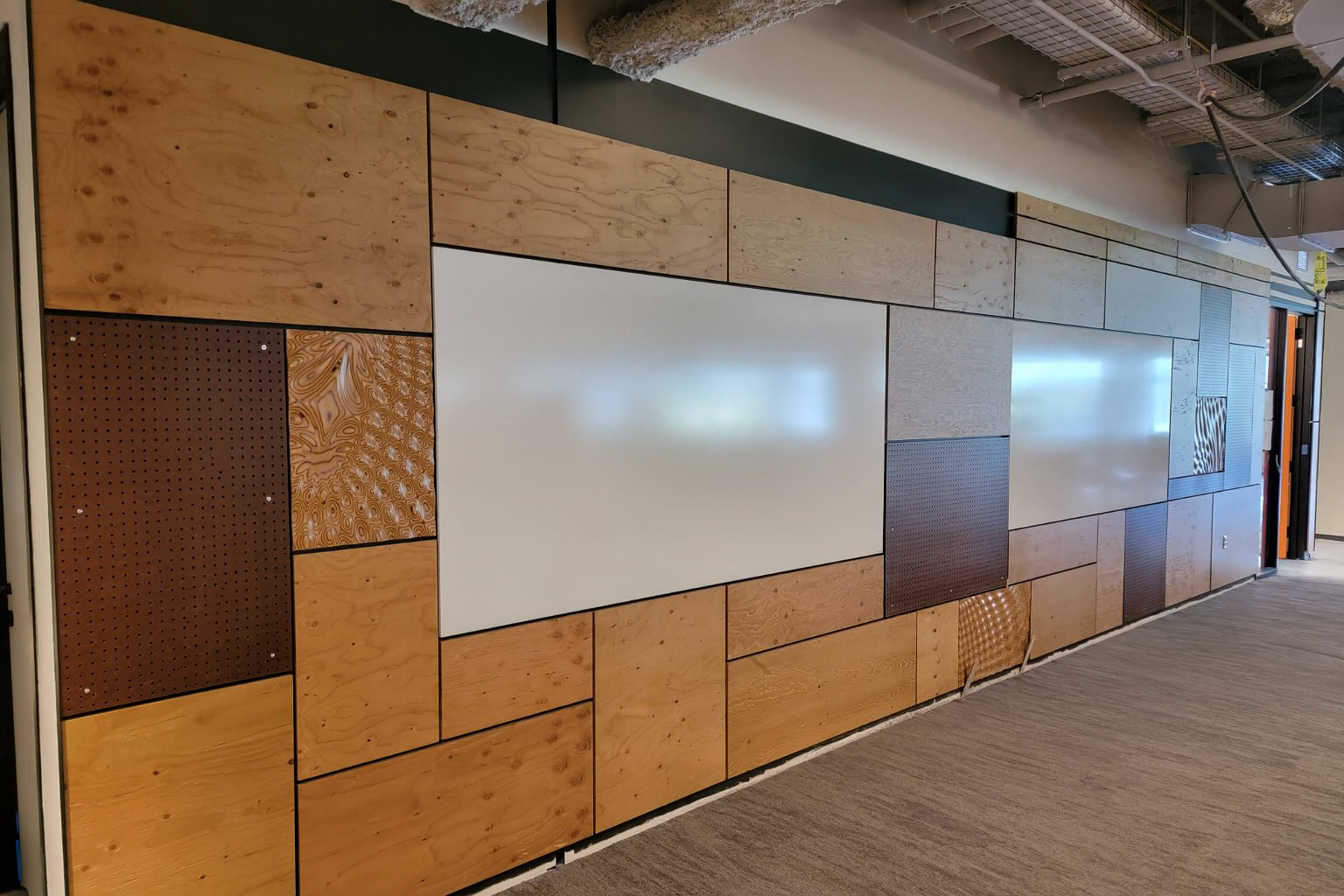 Interior wall with a pattern of wood, metal, and smooth panels of various colors and textures.
