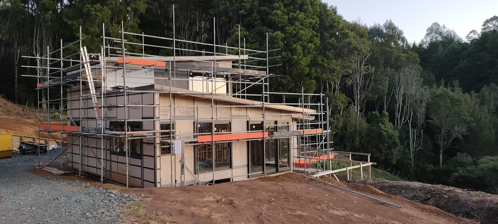 Construction site showing an architectural house build with multiple levels  and a permeable gravel driveway designed for this sloping site overlooking Native NZ bush in Pirongia, NZ.