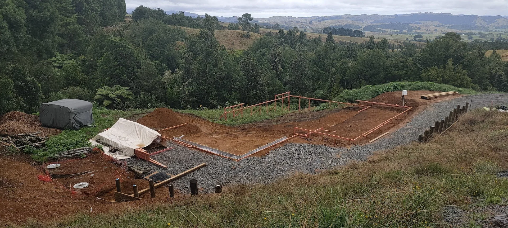 Construction site showing  earthworks, levels and  permeable gravel driveway showing the implementation of a site plan designed for this sloping site overlooking Native NZ bush in Pirongia, NZ 