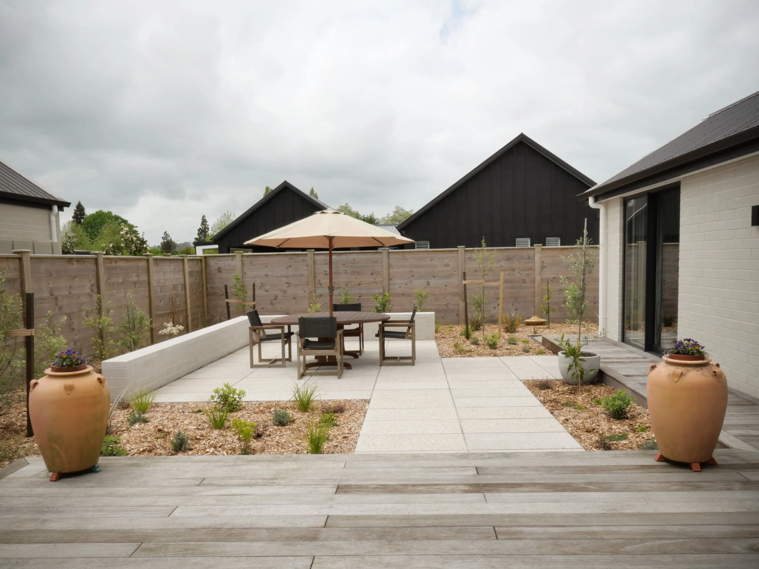 A  modern, fresh courtyard Landscape design featuring a low block wall, Handmade, bespoke concrete pavers and NZ native planting on a small site with no lawn in Cambridge, New Zealand