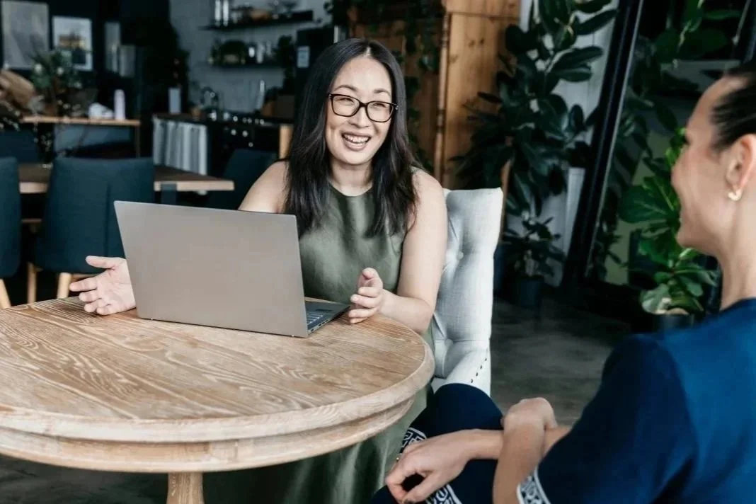 Two people sitting at a table with a laptop