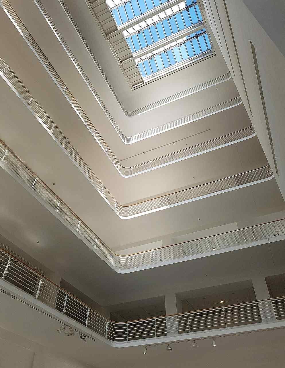View of a multi-story interior atrium with balconies, railings, and a large skylight at the top allowing natural light.