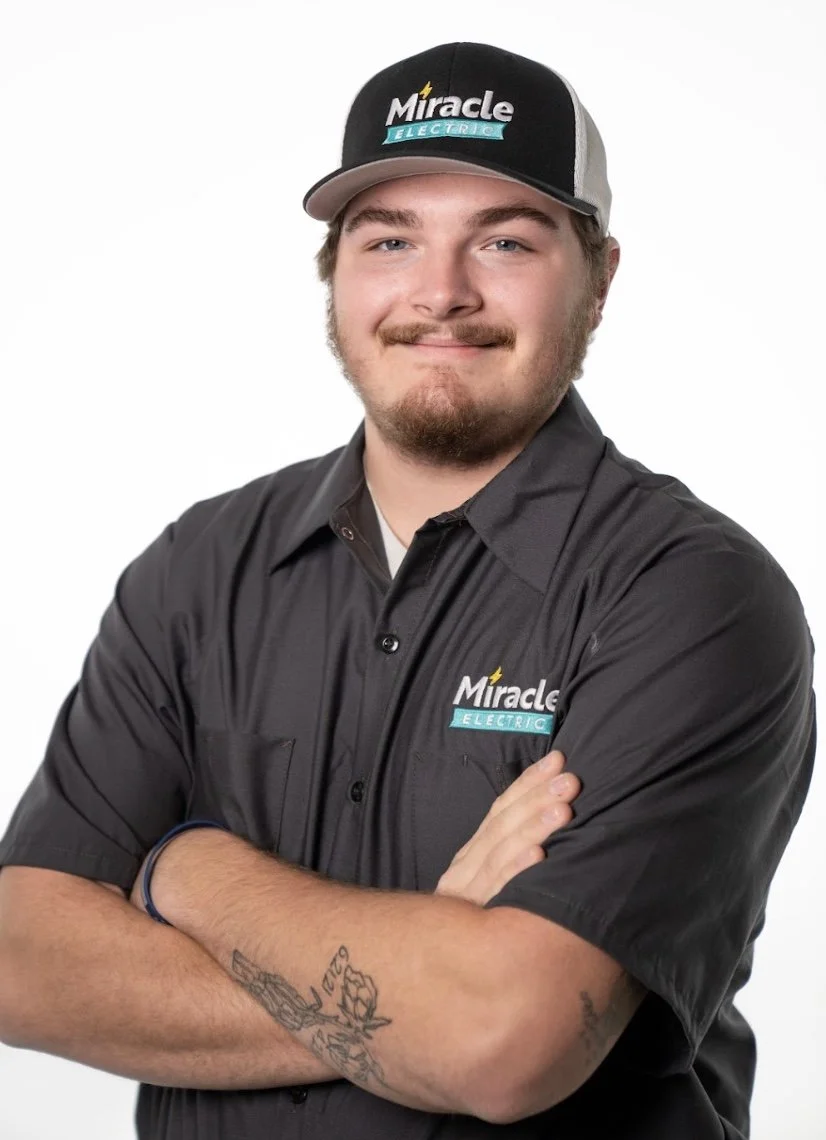 Three people, two young men and a woman, smiling and giving thumbs-up while taking a selfie in a kitchen.
