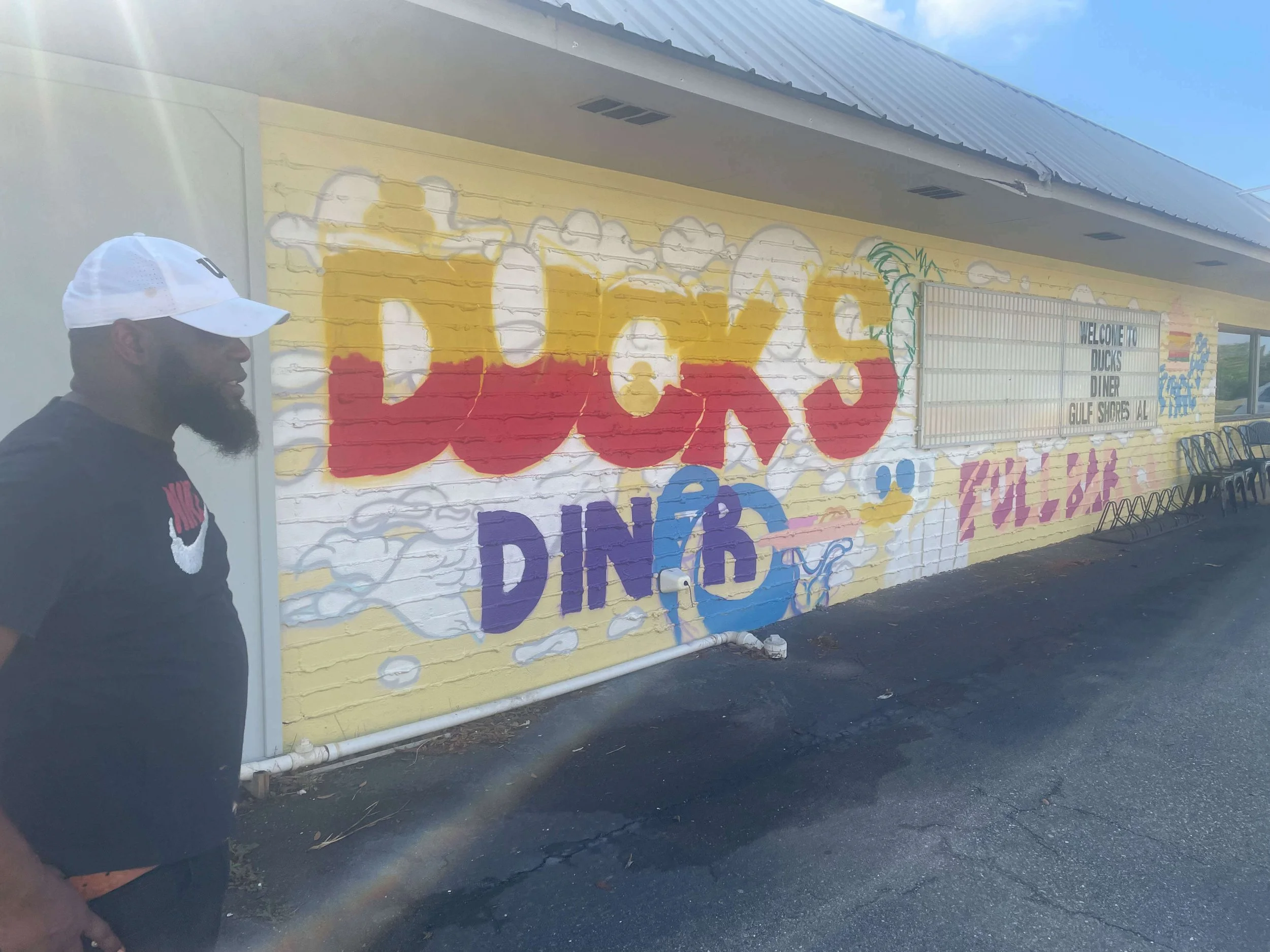 Street art style mural on Duck’s Diner in Gulf Shores, Alabama, progressing with detailed lettering and bold outlines, showcasing vibrant diner branding, 2025.