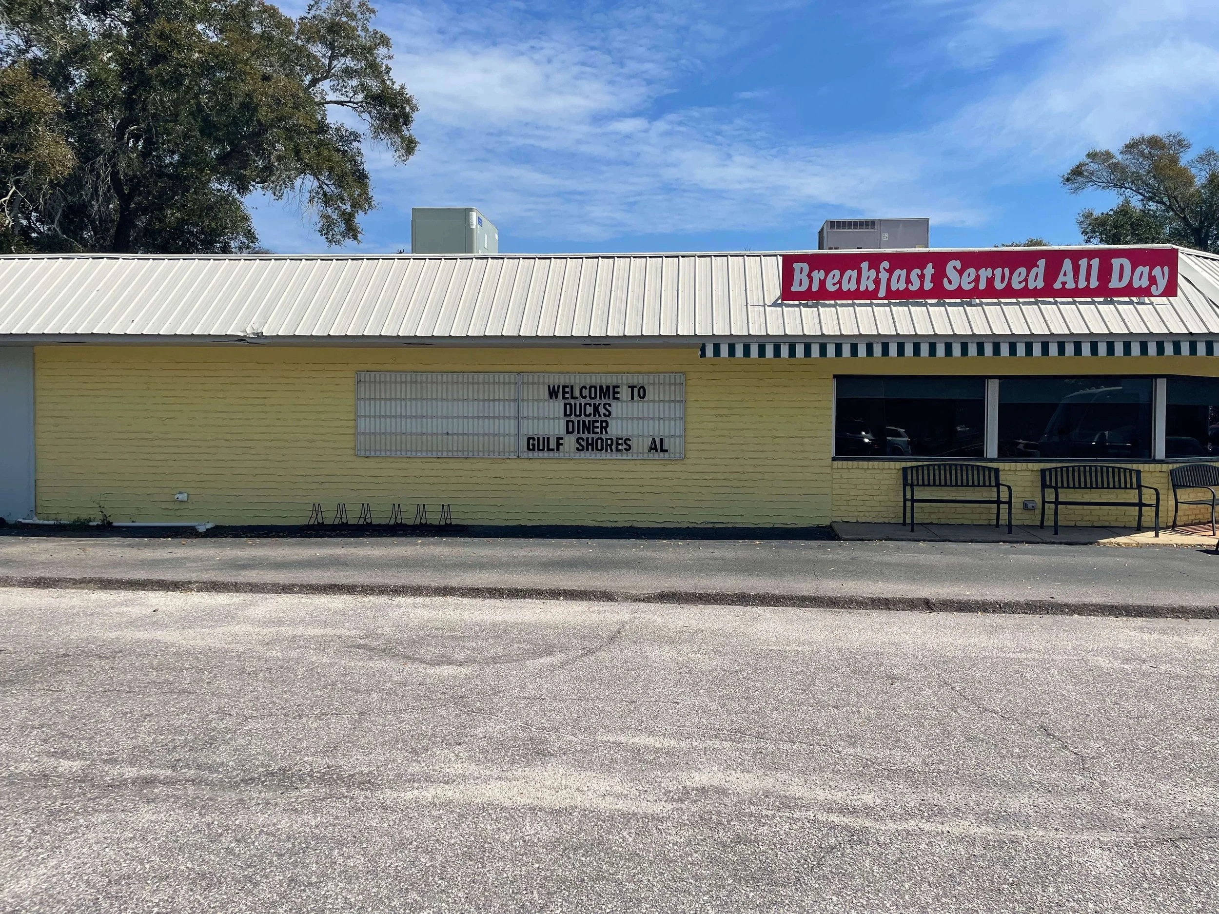 Early stage mural preparation on the exterior of Duck’s Diner in Gulf Shores, Alabama, showing the yellow-painted building wall before detailed artwork begins, 2025.