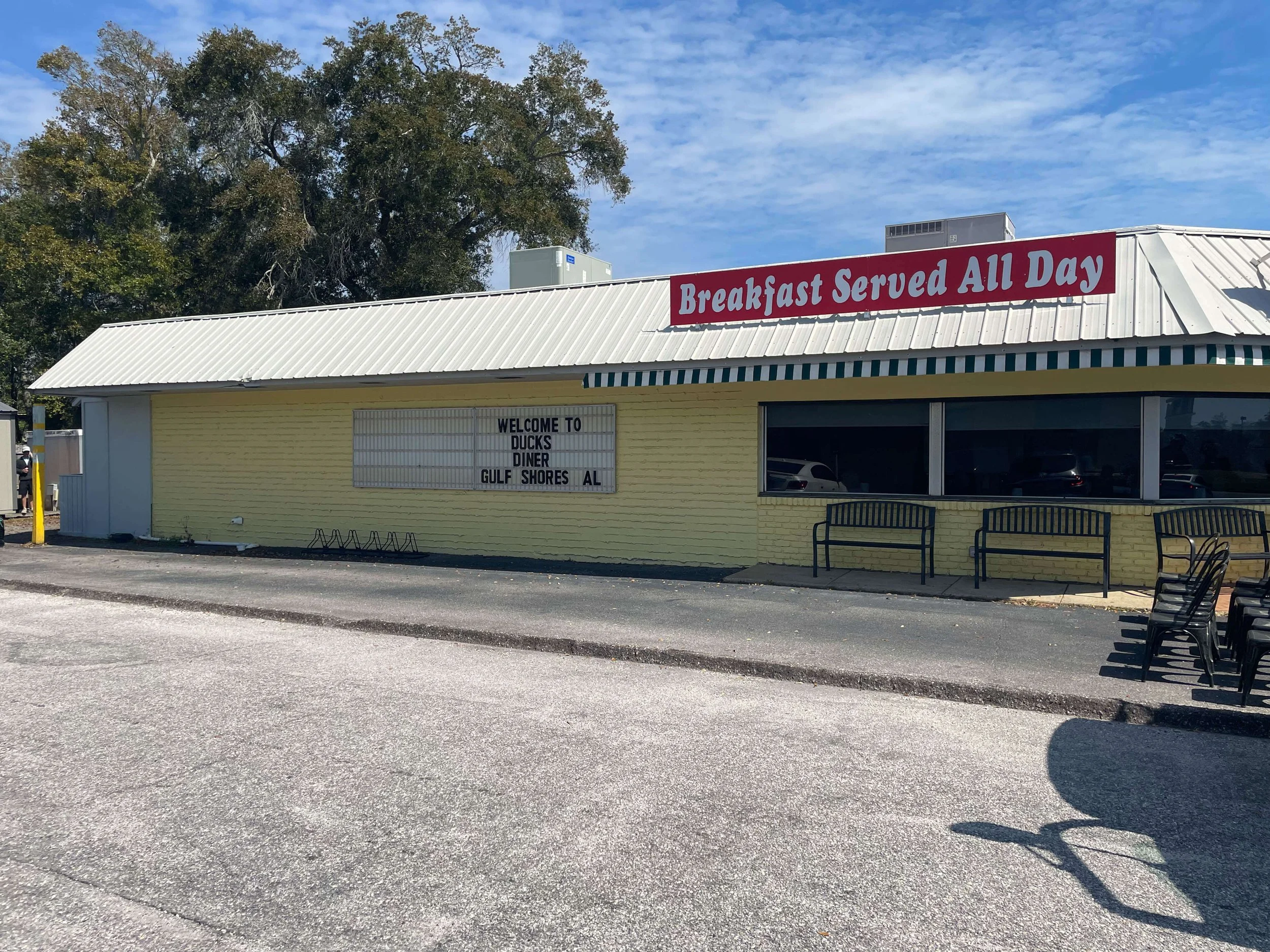 Early stage mural preparation on the exterior of Duck’s Diner in Gulf Shores, Alabama, showing the yellow-painted building wall before detailed artwork begins, 2025.