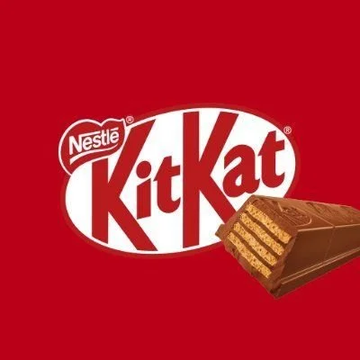 Nestle Kit Kat chocolate bar with a bite taken out of it, showing wafer layers, on a red background with the Kit Kat logo.