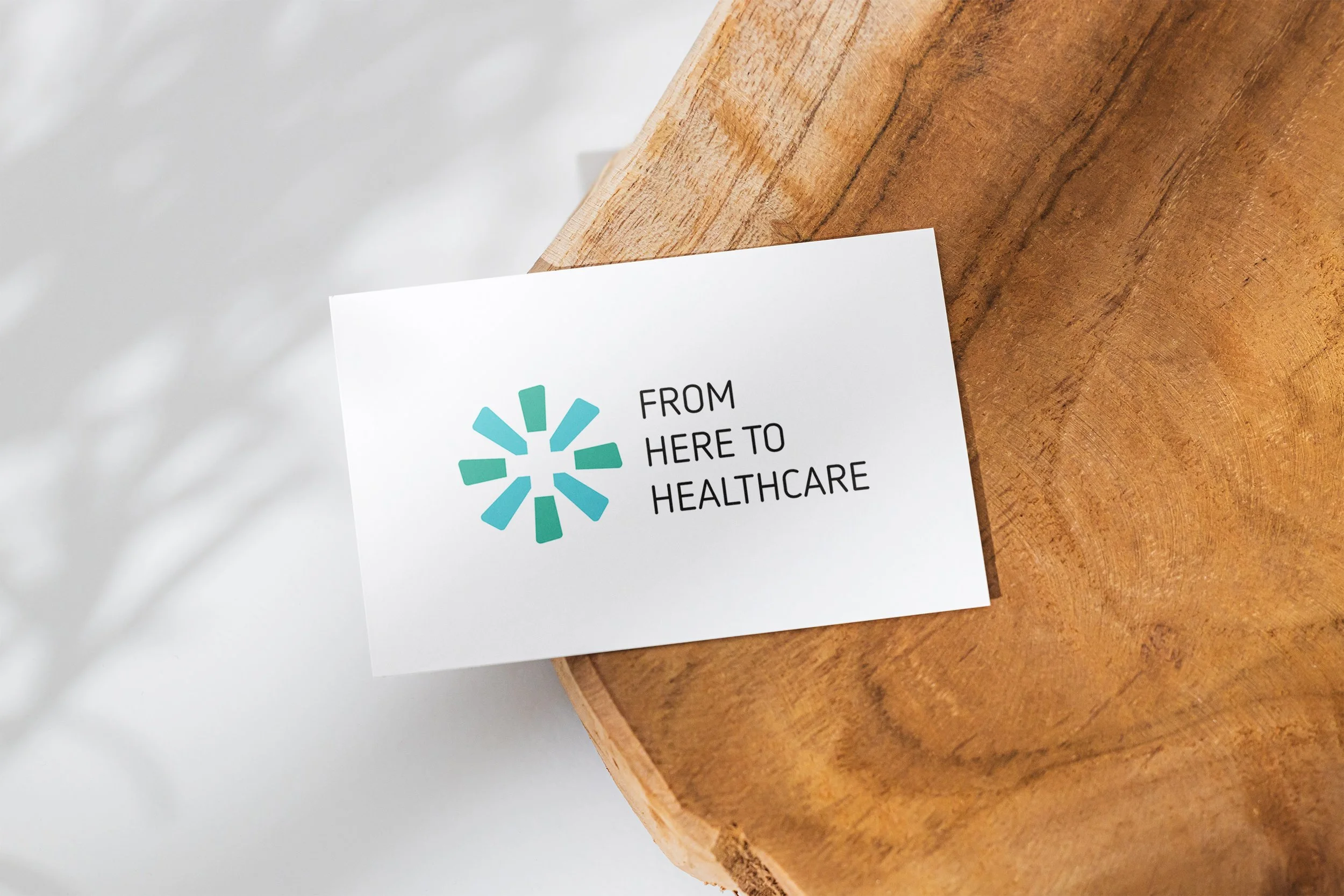 Part of a healthcare flyer with a teal and black logo, on a wooden table surface.