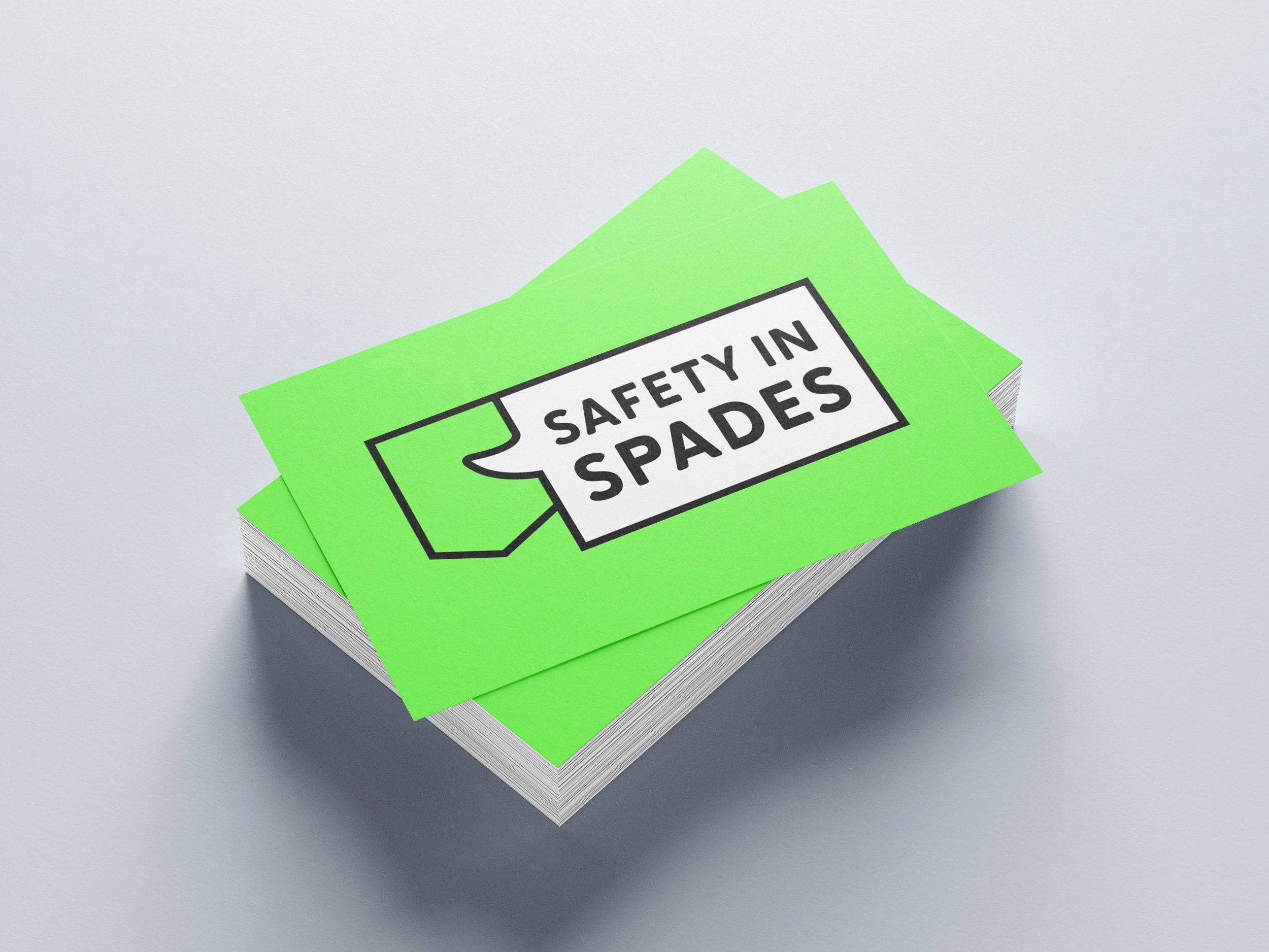 Stack of bright green safety in spades cards with a black outline and text.