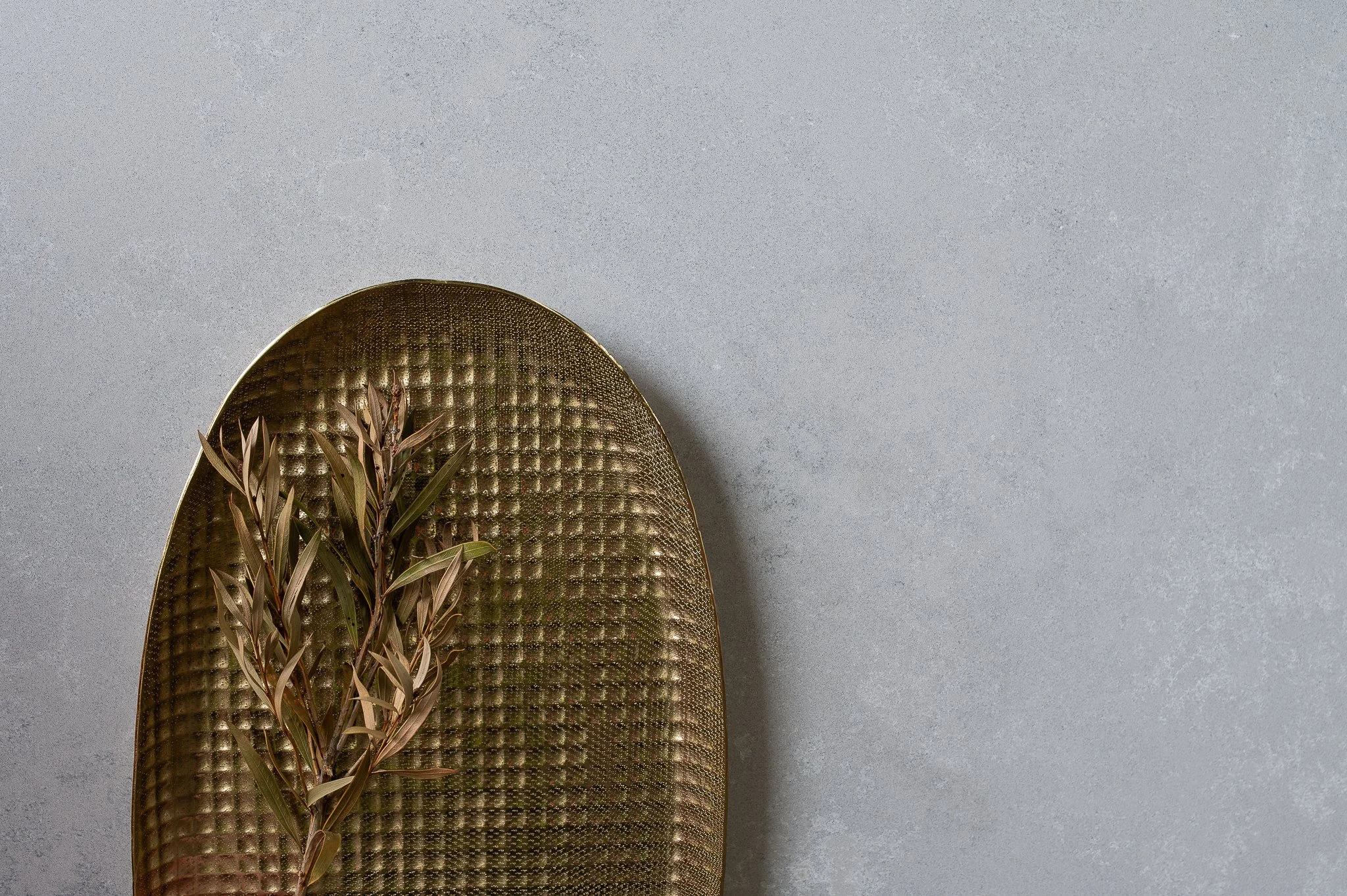 Luxury interior photography featuring curated styling details, natural materials and a textured decorative tray with olive branches.