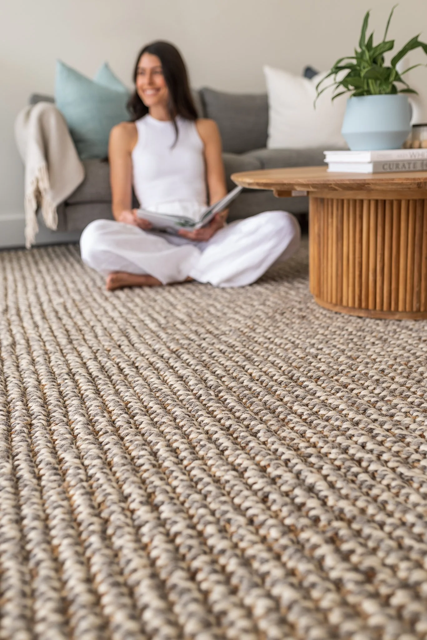 Lifestyle product photo of a woman sitting on a natural pile rug in a Glenelg home.