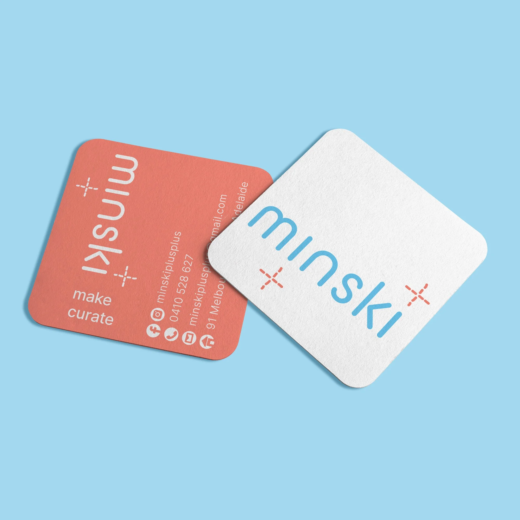 Two business cards, one orange and one white, on a light blue background. The orange card displays LinkedIn, Facebook, Instagram, and email icons, with contact information, while the white card features the name 'Minski ++' in text.