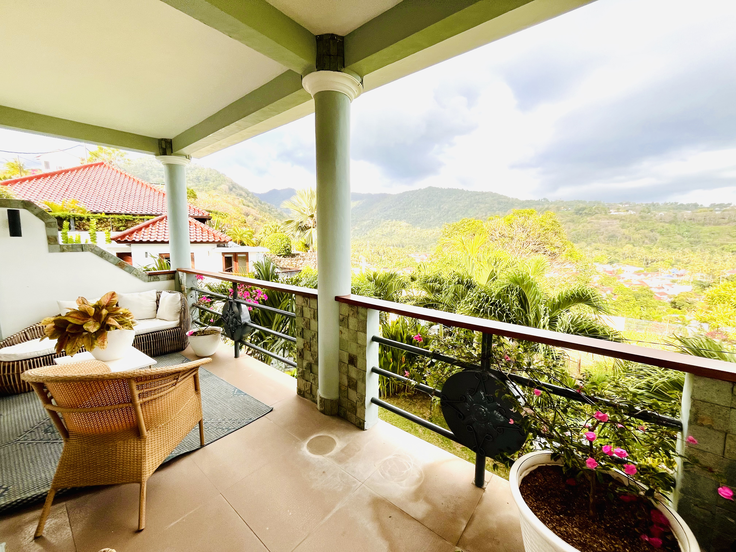 A balcony with outdoor furniture, potted plants, and a view of beautiful Green Valley.