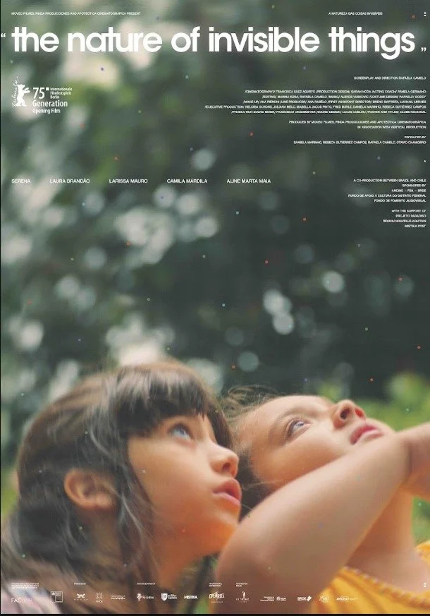 Poster for The Nature of Invisible Things. Two young girls lie on the grass looking up, surrounded by soft green foliage.