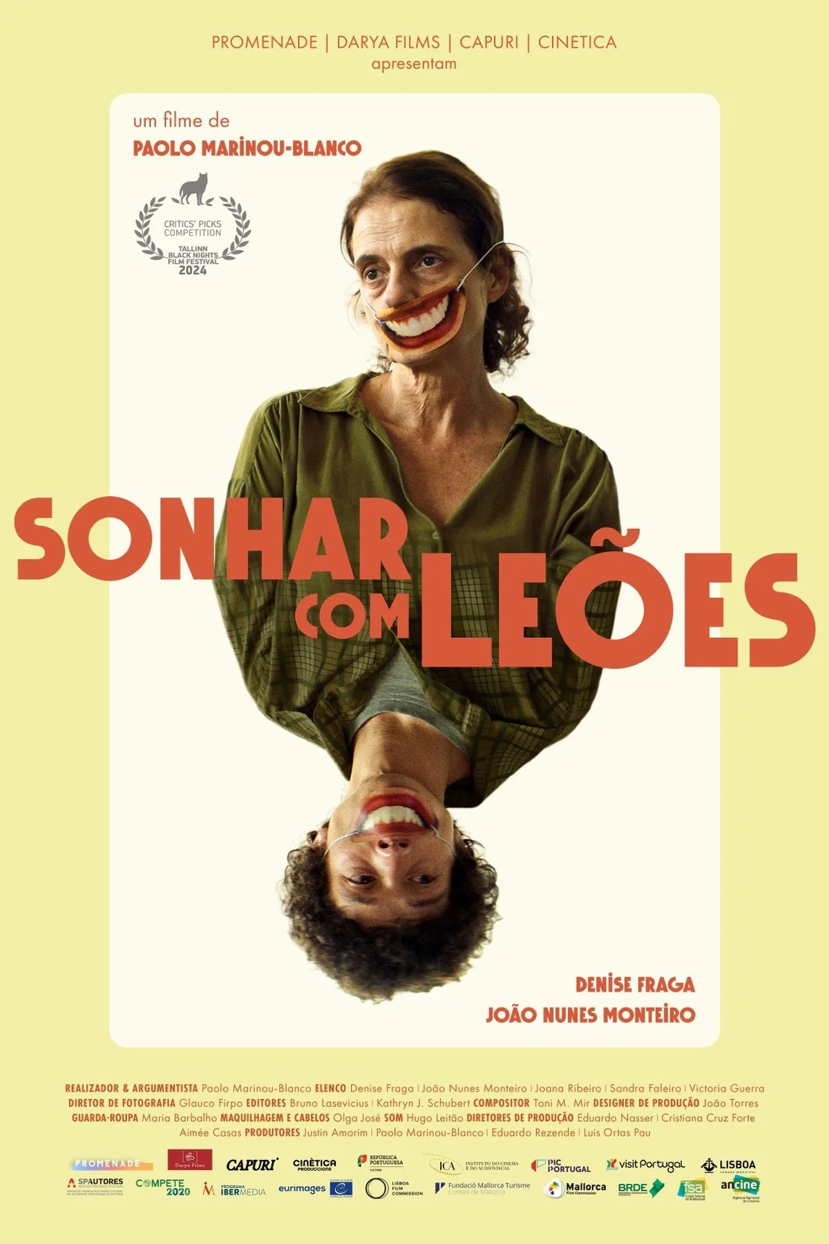 Poster for Dreaming of Lions. A woman with a painted smile is shown upside down on a pale yellow background, with the title in large orange letters.