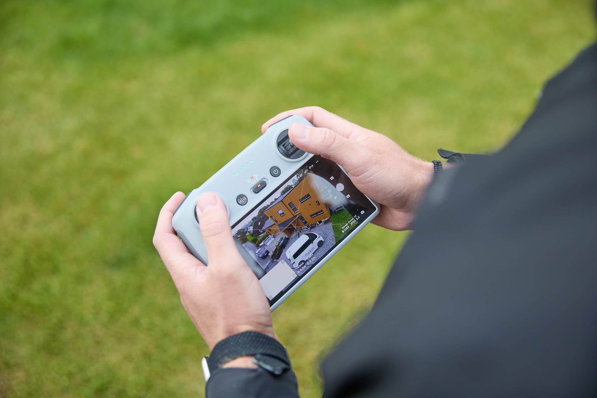 Person som tar et bilde av en moderne bolig med en mobiltelefon.