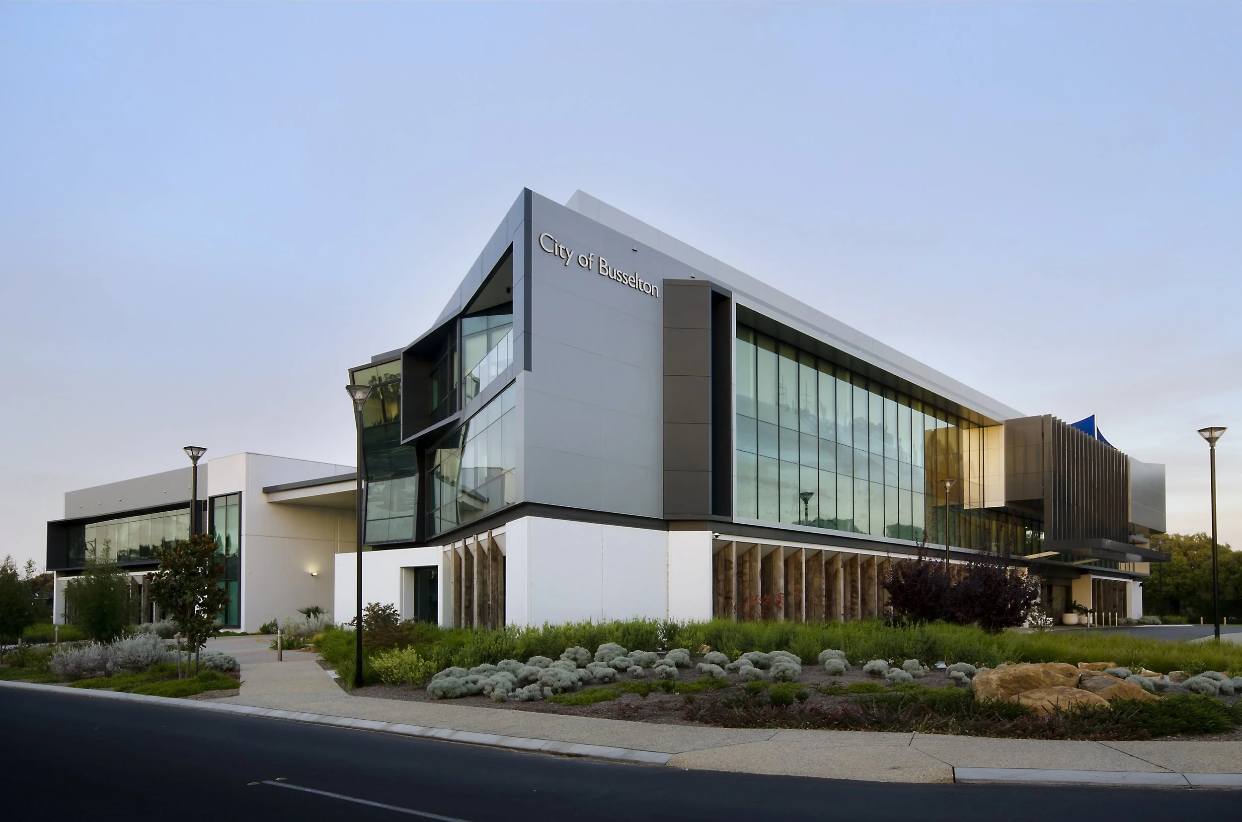 Modern multi-story city hall building with glass exterior and landscaped front yard, labeled City of Busselton.