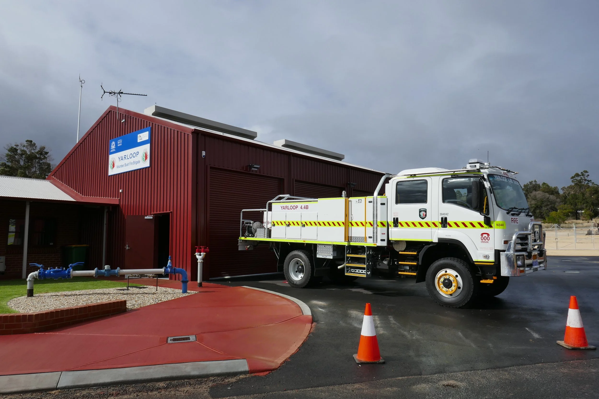 Fire truck parked outside a fire station with a sign labeled 'YARLOOP,' on a partly cloudy day.