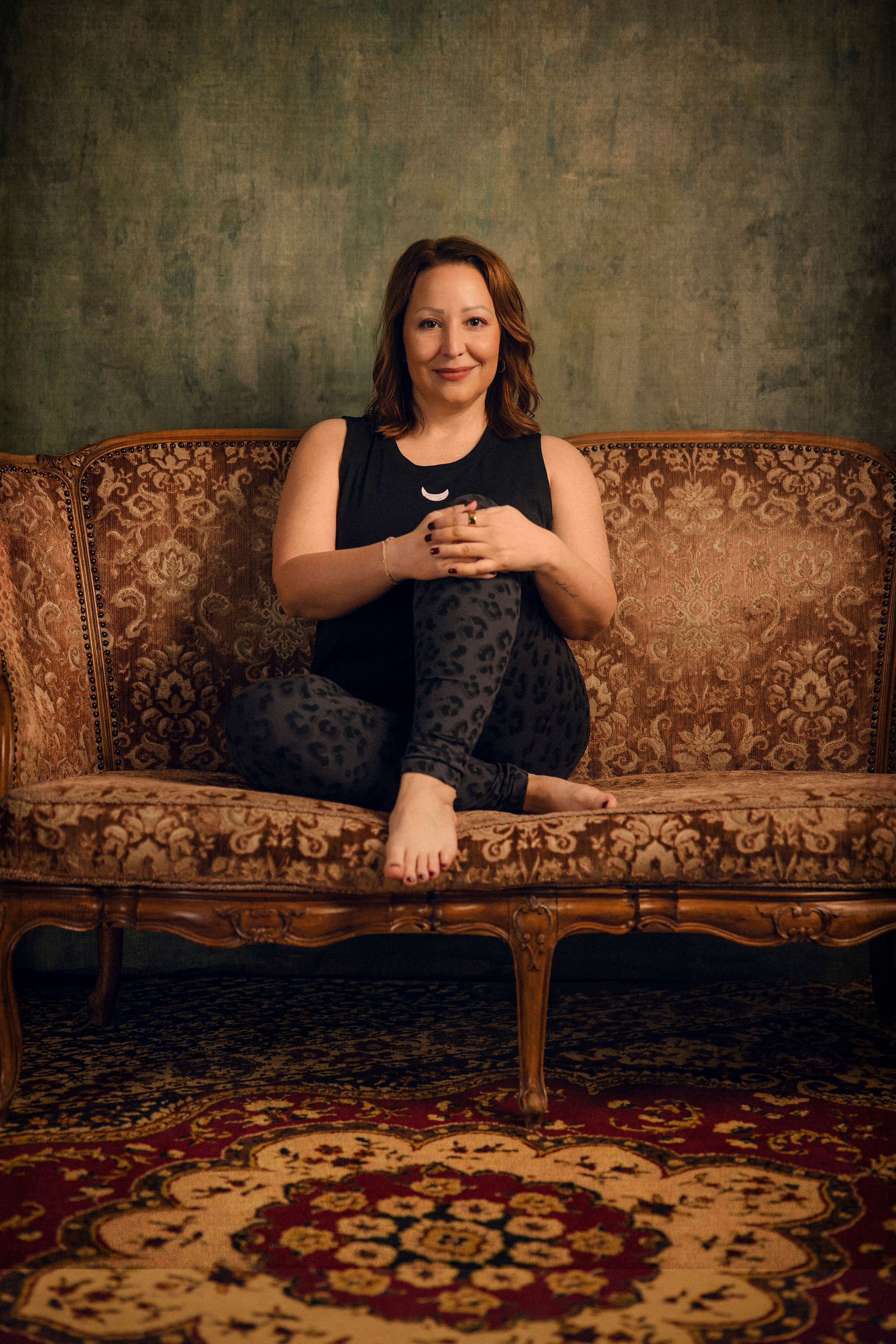 Frau in Yogapose auf Retro Couch lächelnd