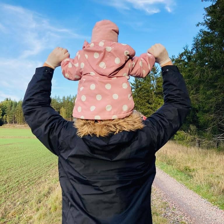 Man går promenad med sin dotter sittandes på axlarna.