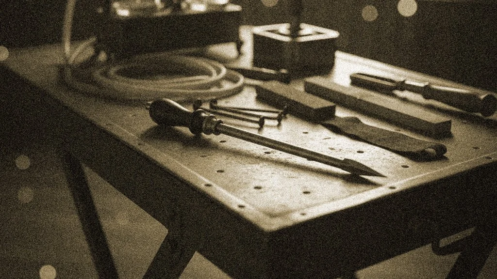 A workshop workbench with hand tools including screwdrivers, chisels, and a pick, illuminated in sepia tone.
