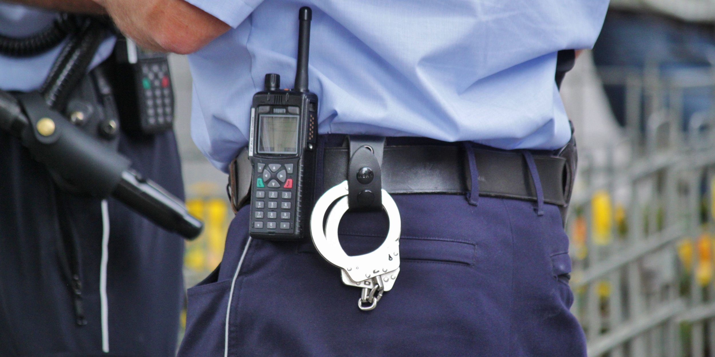 Close-up of police officer's waist with radio, handcuffs, and other equipment attached to the belt.