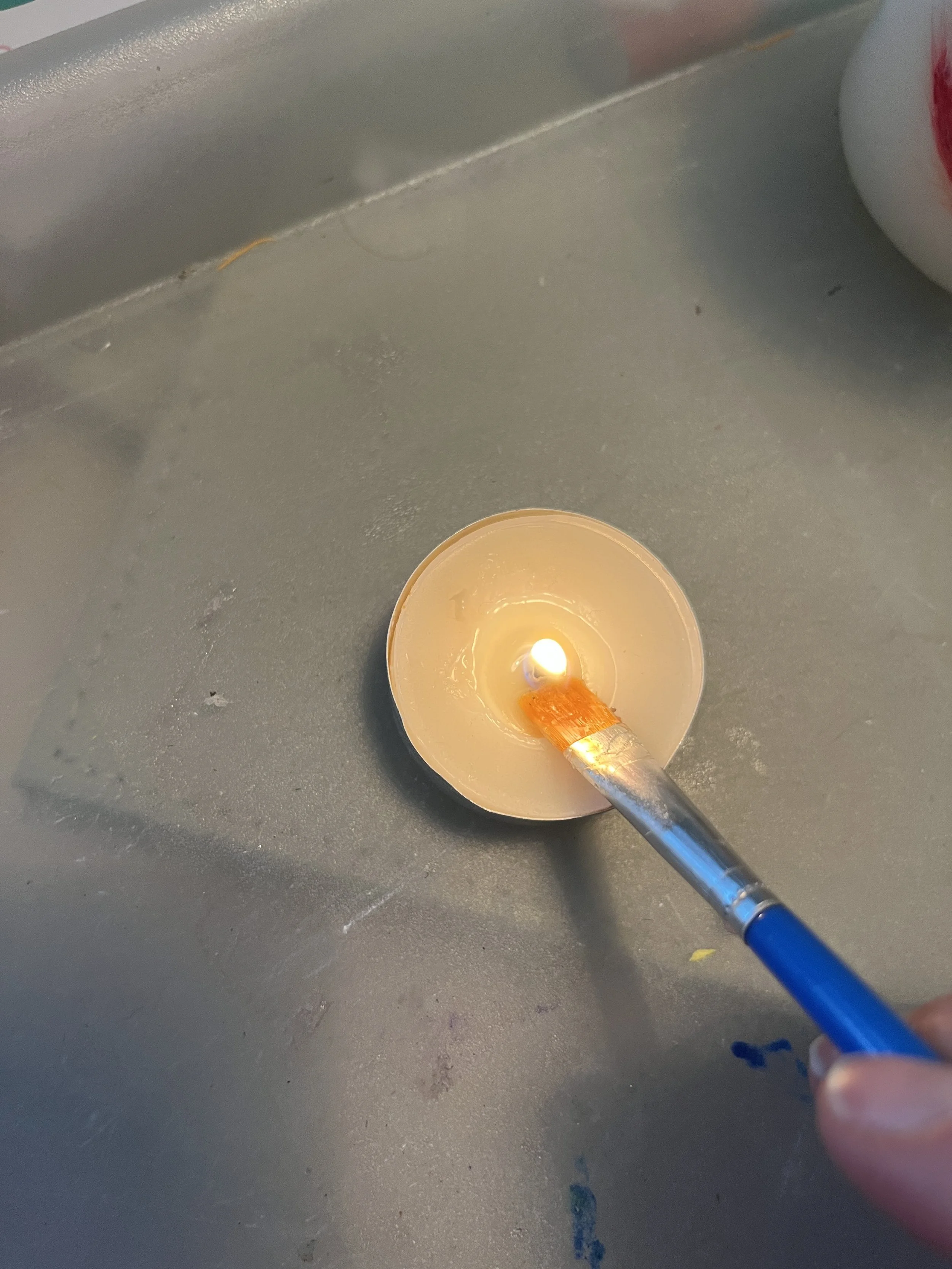 1. Gather all your materials and start by lighting one of your tealights using a lighter or match. Wait until the wax has started to melt before starting. 