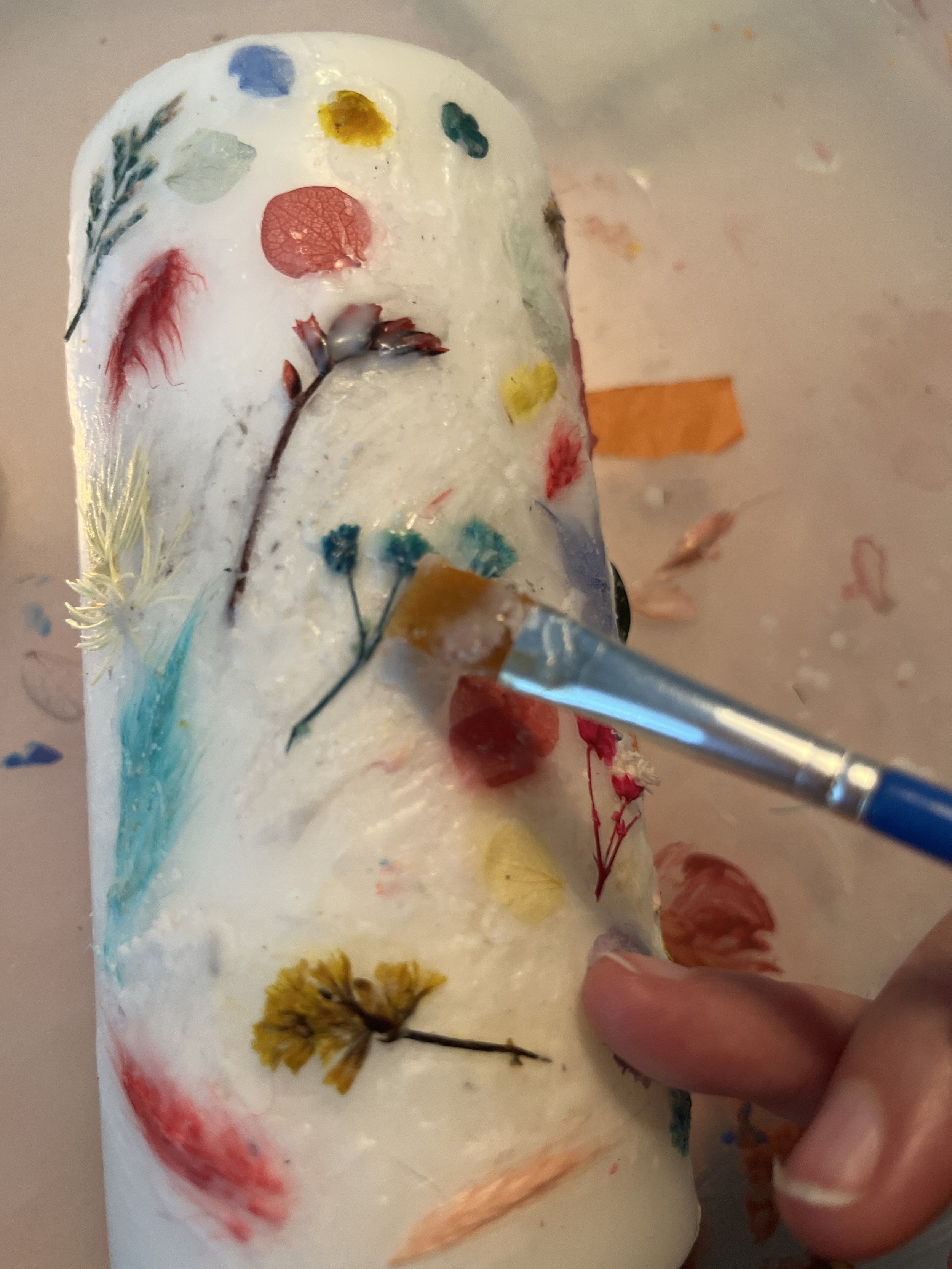 2. Once you have a 'pool' of wax in the tea light, you can use the wax to 'press' your dried flowers into the pillar candle. You may want to break up some of the larger flowers. It also helps to pop a little wax on the candle first to allow the flowe