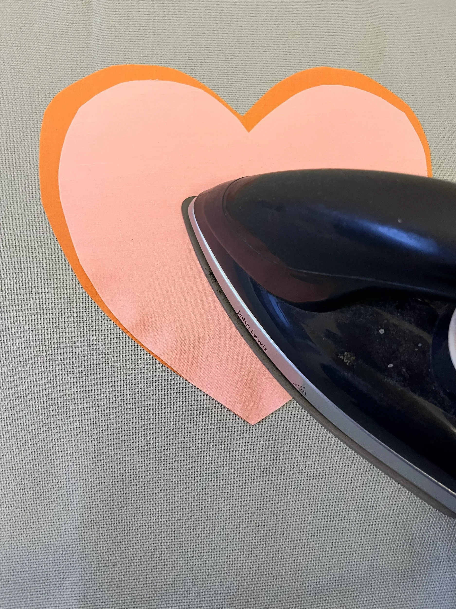 7. Once you are happy with the placement, again iron over the top for a couple of seconds to bond the second, smaller heart to the larger one. 