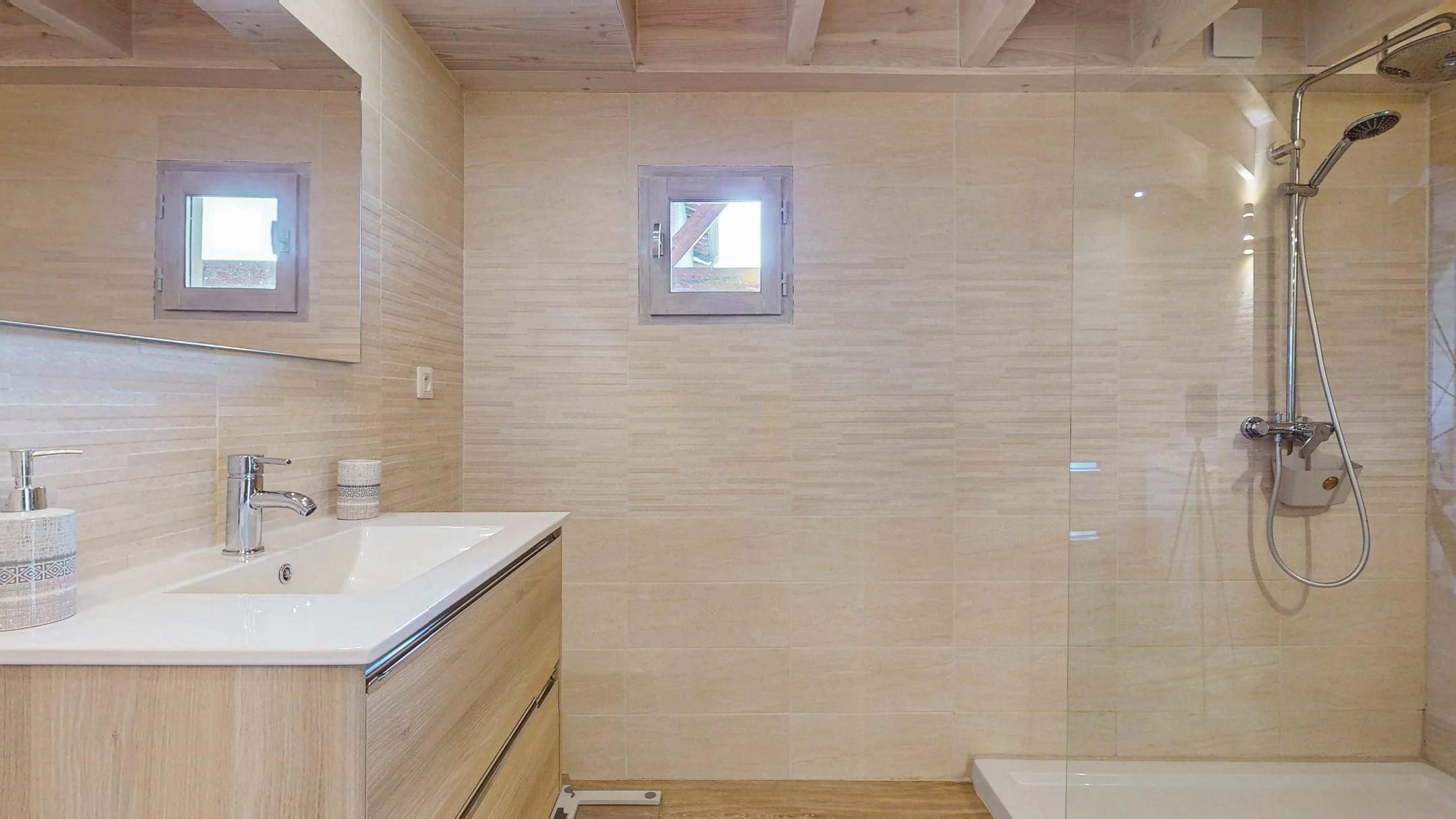 Salle de bain moderne avec deux petites fenêtres, lavabo avec miroir, douche à l'italienne et décoration neutre.