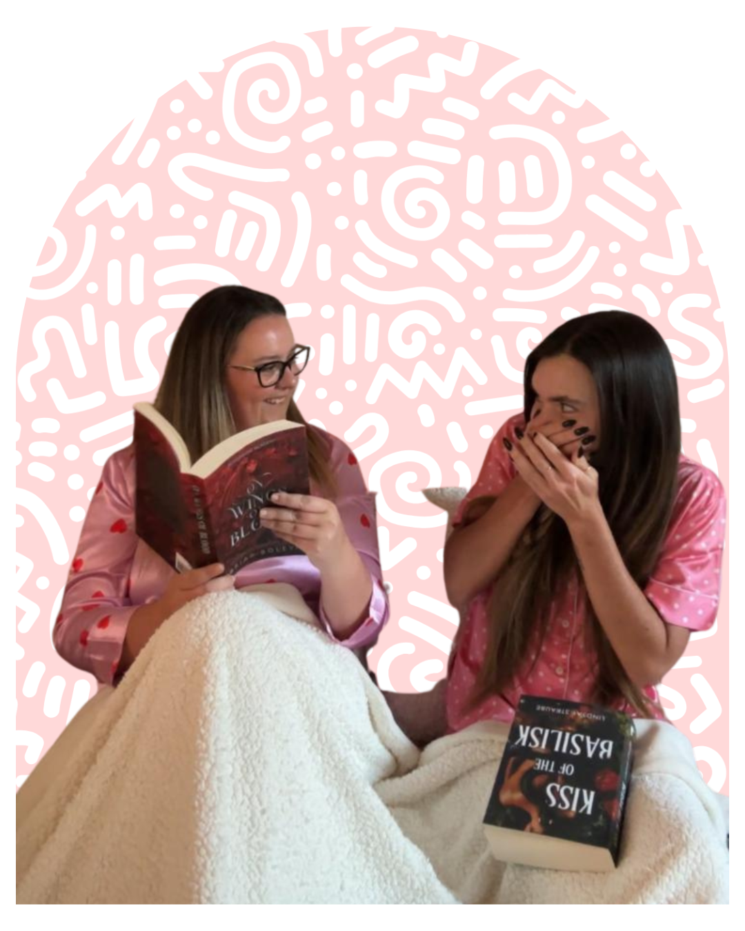 Two women sitting close together, wearing pink pajamas, sharing a blanket, with a pink and white abstract background. One woman is reading a book titled 'Kiss of the Basilisk,' and the other is covering her mouth, appearing surprised or amused.