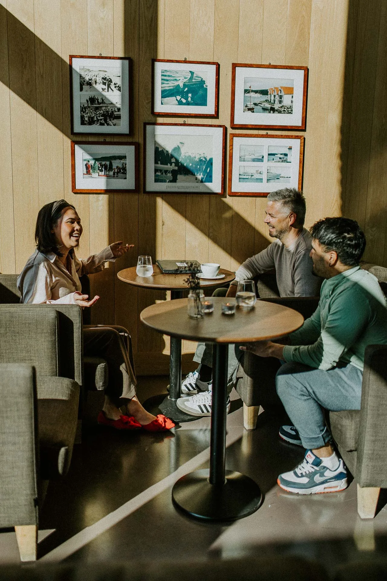 Reklamefotografering til kampanje for Altibox bedrift tatt i naturlig lys tre personer i dialog sittende i restaurant hardt sollys