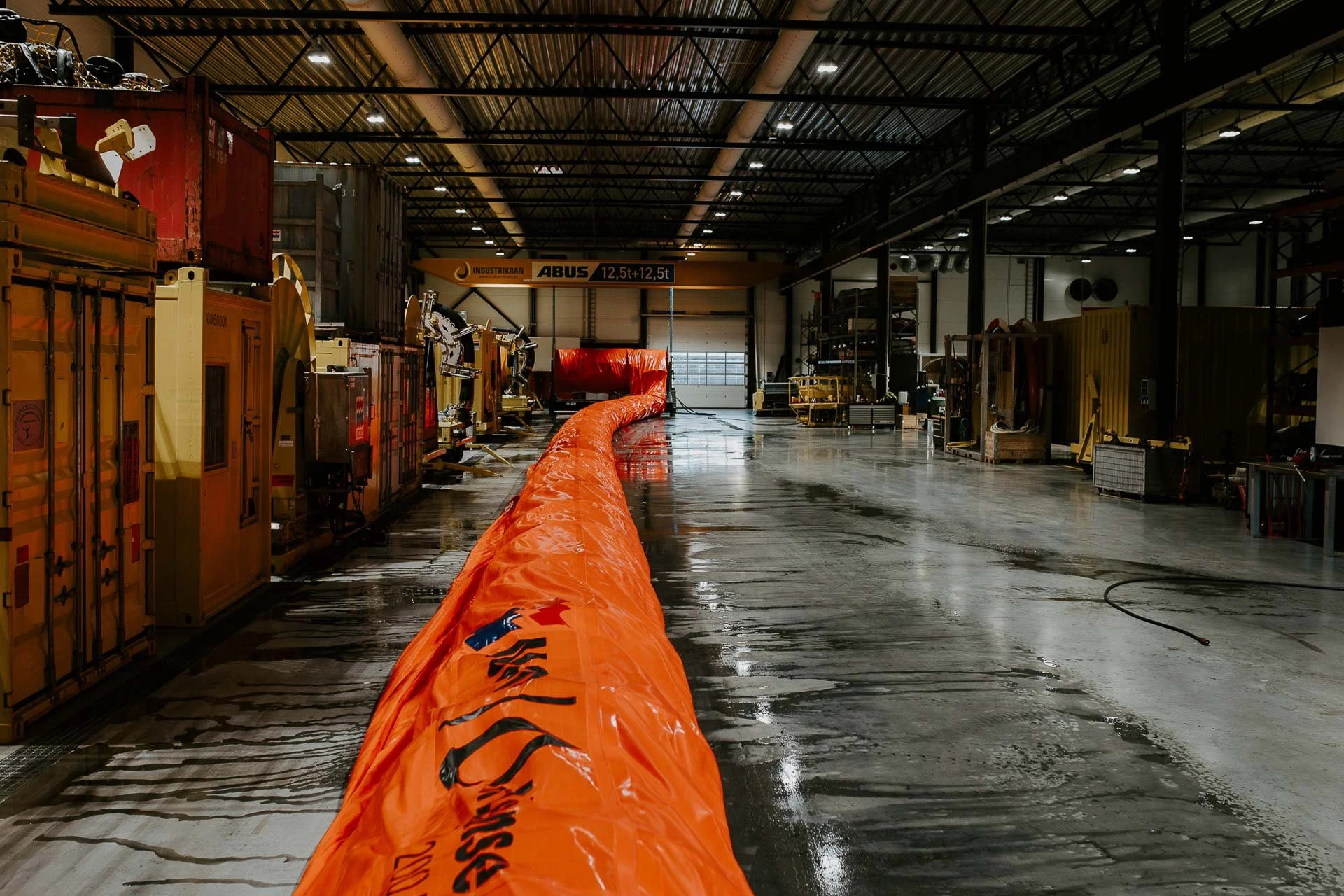 Oversiktsbilde inne på verksted hos Nofo oransje slange ligger utover gulvet reklamefotografering for nofo norsk oljevernberedskap tatt i naturlig lys