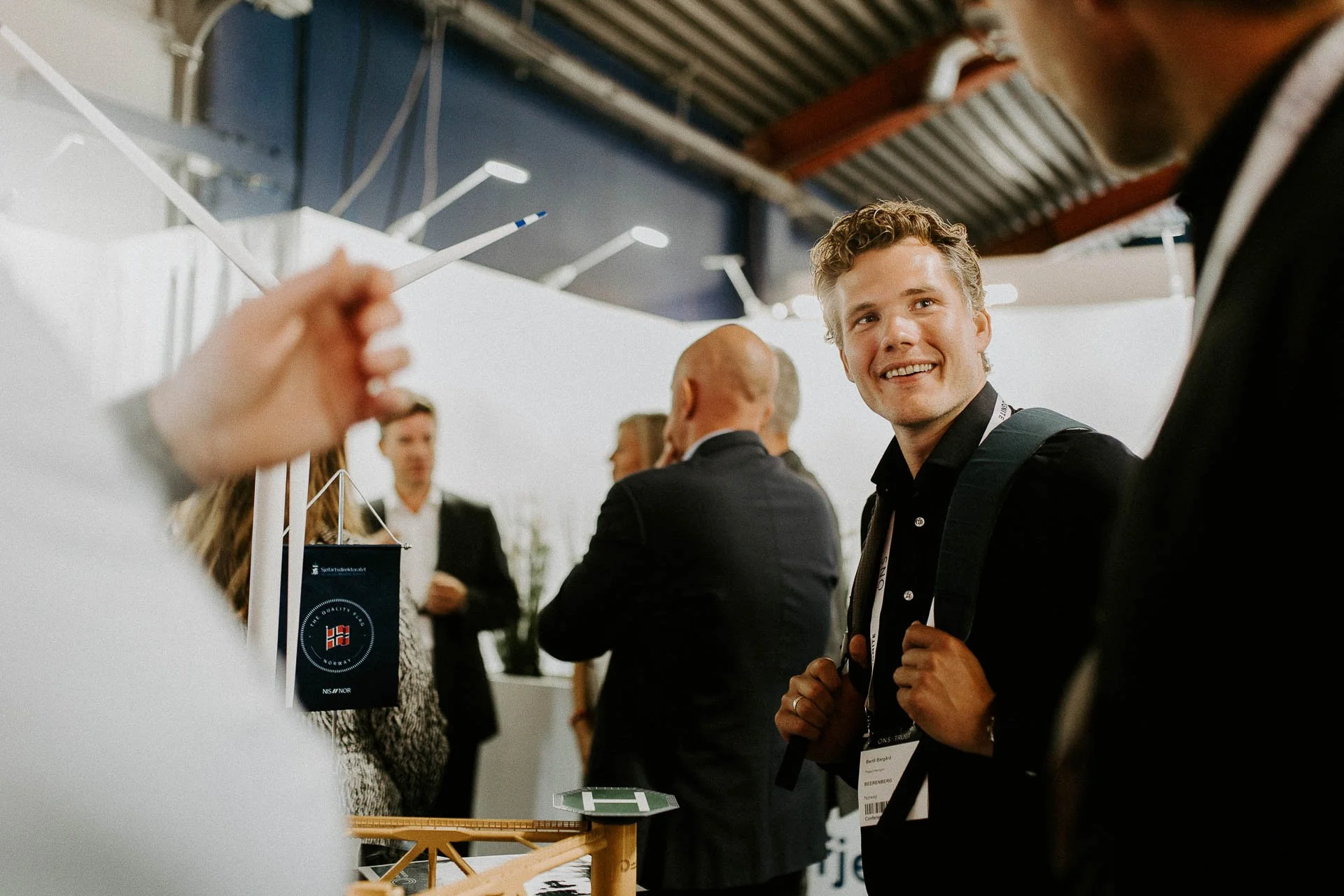 mann smiler og ser på en annen person han har ryggsekk på og ONS adgangskort på dokumentarfotografering for ONS, Offshore Northern Seas i Stavanger, stavanger forum