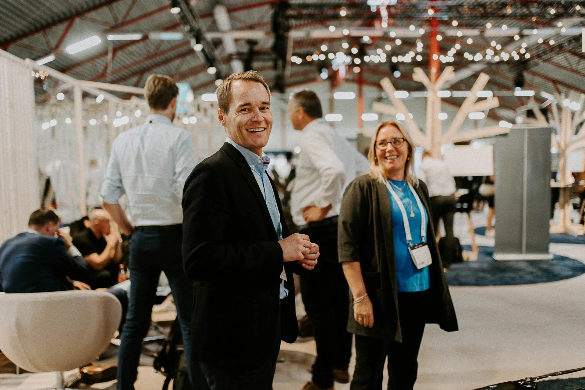 To personer som går rundt og ser på standard har adgangskort på en mann og en kvinne dokumentarfotografering for ONS, Offshore Northern Seas i Stavanger, stavanger forum smiler man ser i kamera