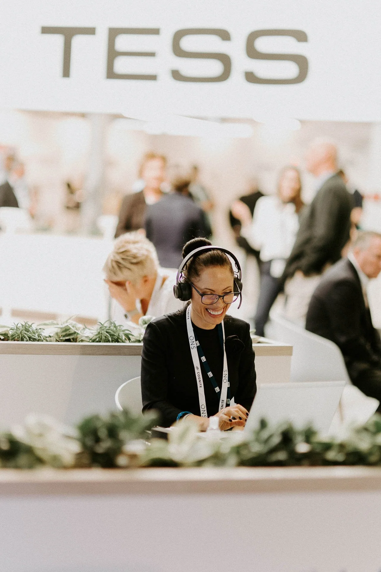 En kvinne har headset på snakker med noen via skjerm i bakgrunnen står logoen TESS hun smiler dokumentarfotografering for ONS, Offshore Northern Seas i Stavanger, stavanger forum