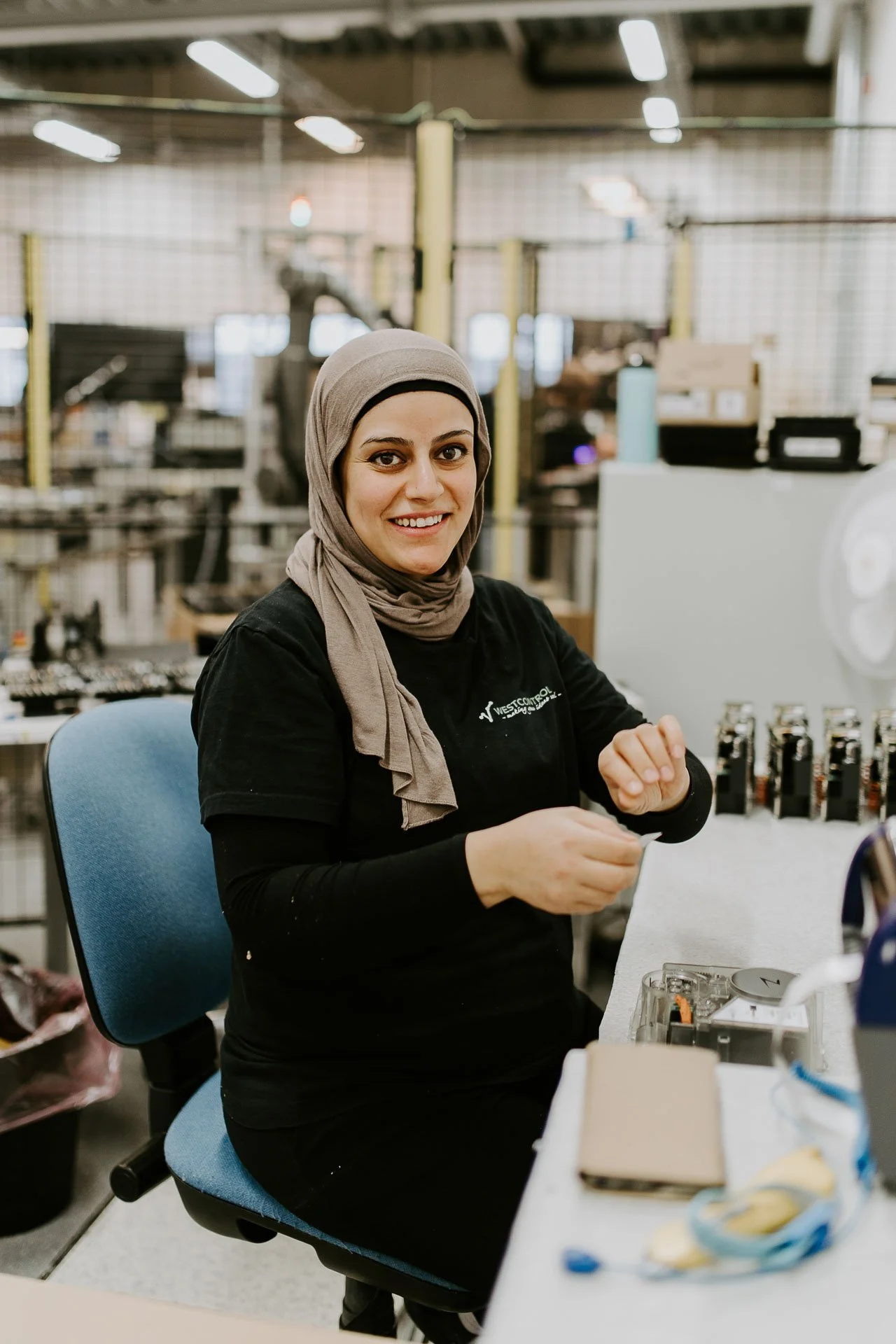 Kvinne som jobber og ser rett i kamera og smiler hun sitter på en blå kontorstol fotografering for zaptec til kampanjebruk og presse naturlig lys