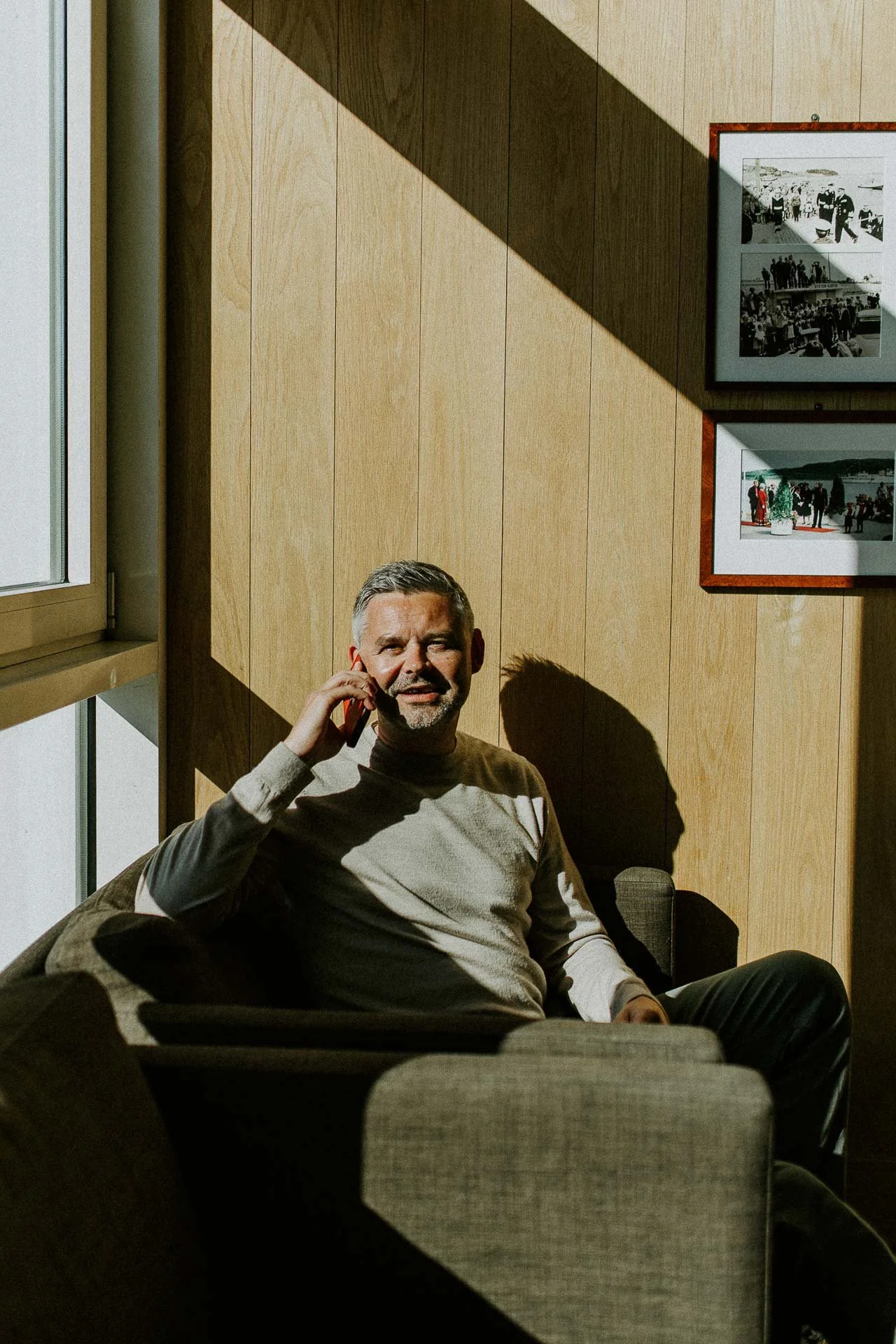 Reklamefotografering til kampanje for Altibox bedrift tatt i naturlig lys ansatt  som snakker i mobiltelefon sitter i stol i skrått sollys utstein klosterhotell