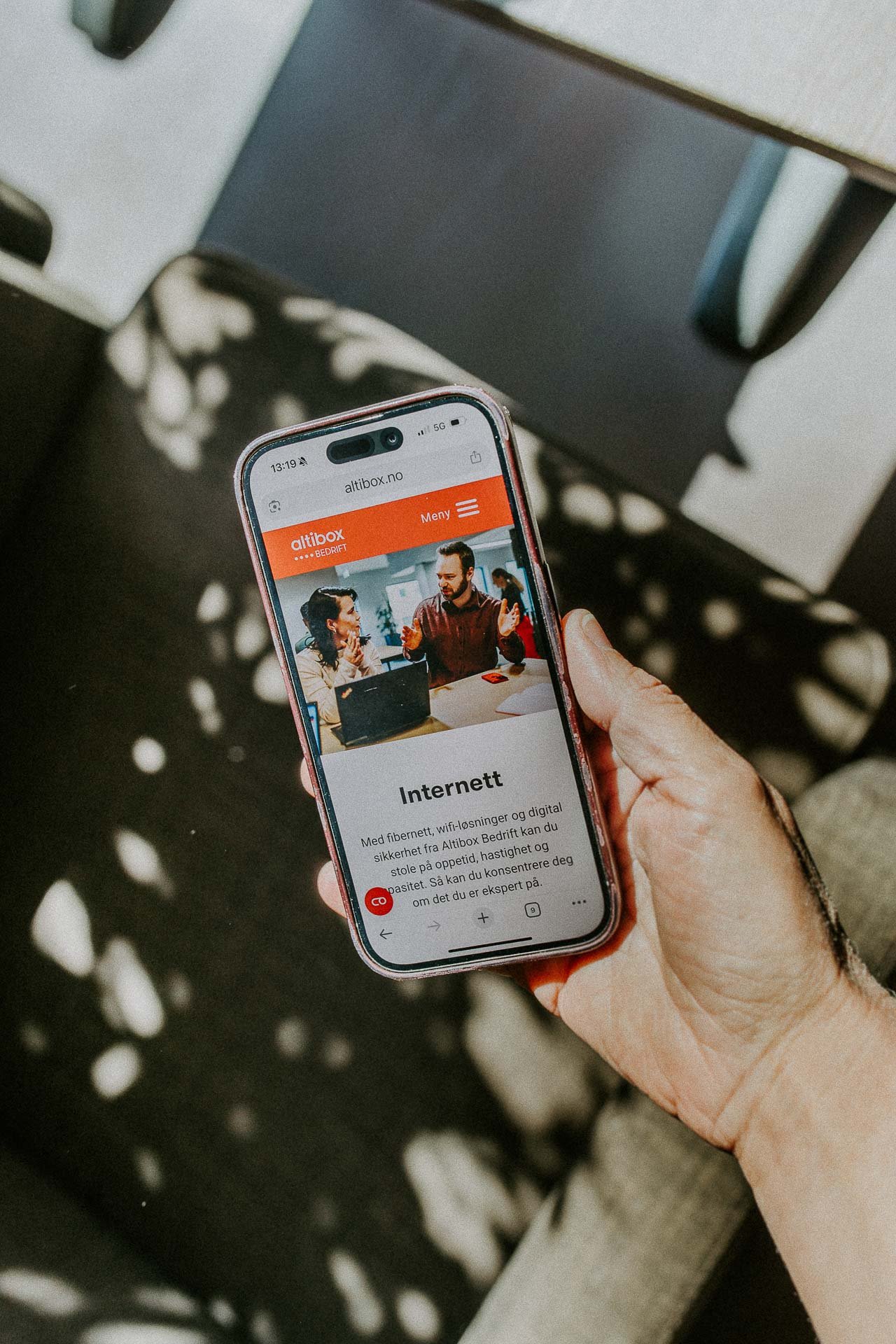 Reklamefotografering til kampanje for Altibox bedrift tatt i naturlig lys utstein kloster hotell hånd som holder mobiltelefon med altibox sin nettside kraftige skygger i bakgrunnen