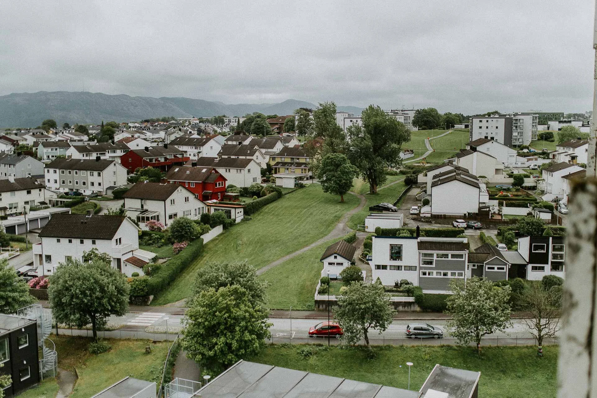 Oversiktsbilde tatt fra høyblokk i Hillevåg men ser hus trær og en sti som snor seg bakover i bildet fjellet bakgrunn naturlig lys, reklamefotografering for stavanger kommune, områdesatsingen i hillevåg