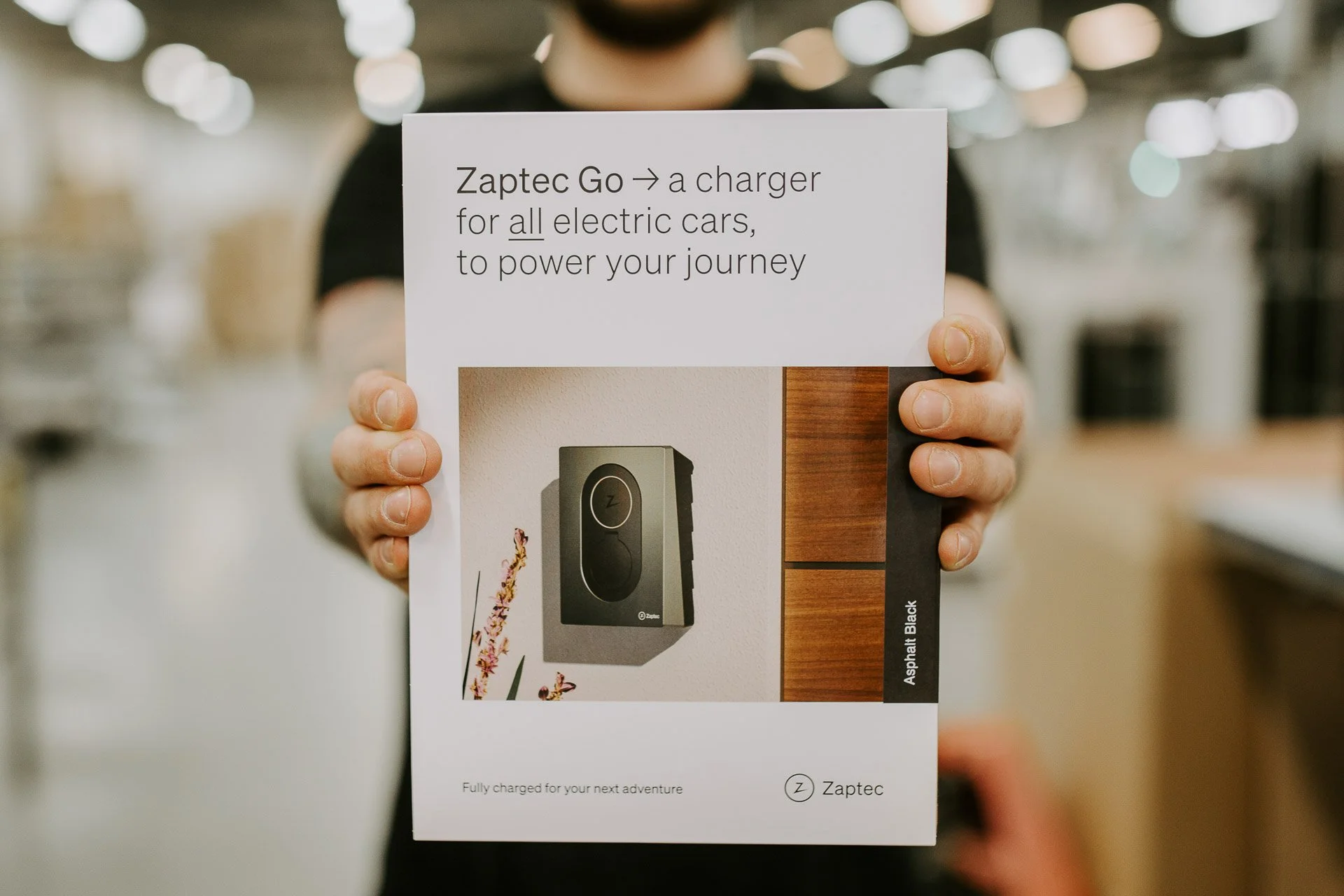 Bilde av mann som holder en eske med en lader ladeboks. fotografering for zaptec til kampanjebruk og presse naturlig lys verksted westcontrol