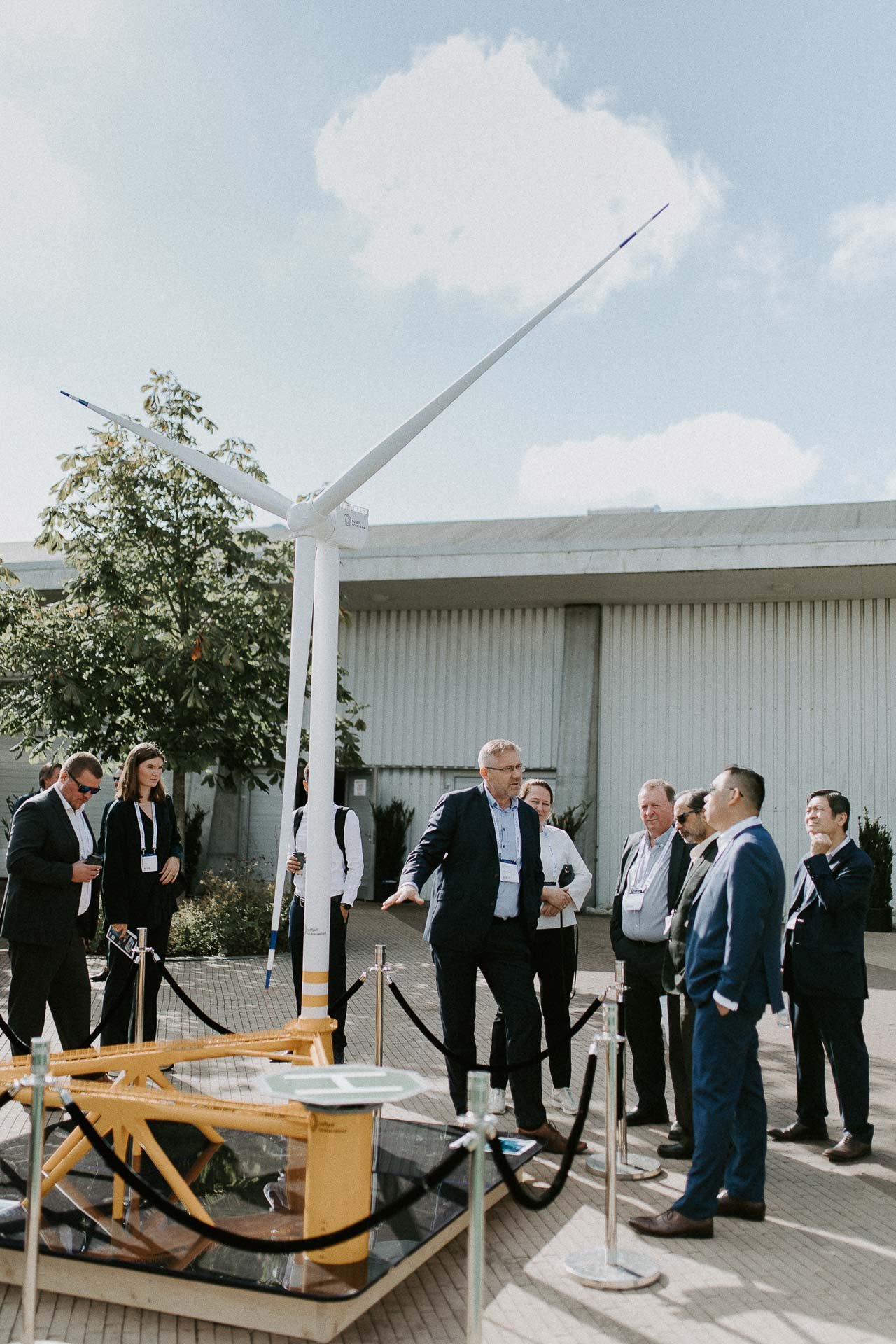 Mange menn står ved vindmølle igjen forklarer bildet tatt utendørs trær bygg og skyer i bakgrunnen dokumentarfotografering for ONS, Offshore Northern Seas i Stavanger, stavanger forum