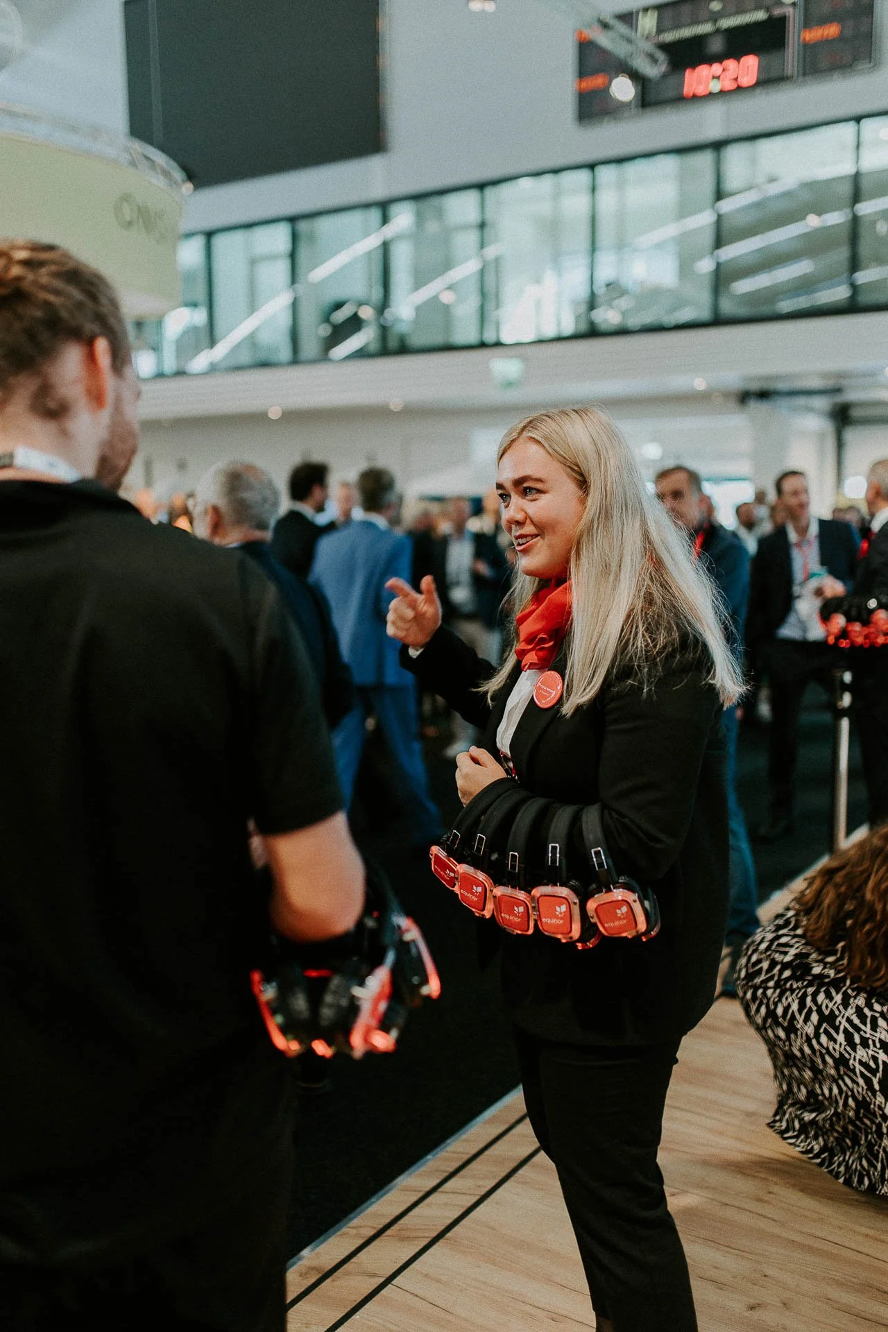 Kvinne som forklarer noe holder mange headset i hånda jobber for Equinor hun smiler og peker tatt inn i hallen mange mennesker i bakgrunnendokumentarfotografering for ONS, Offshore Northern Seas i Stavanger, stavanger forum