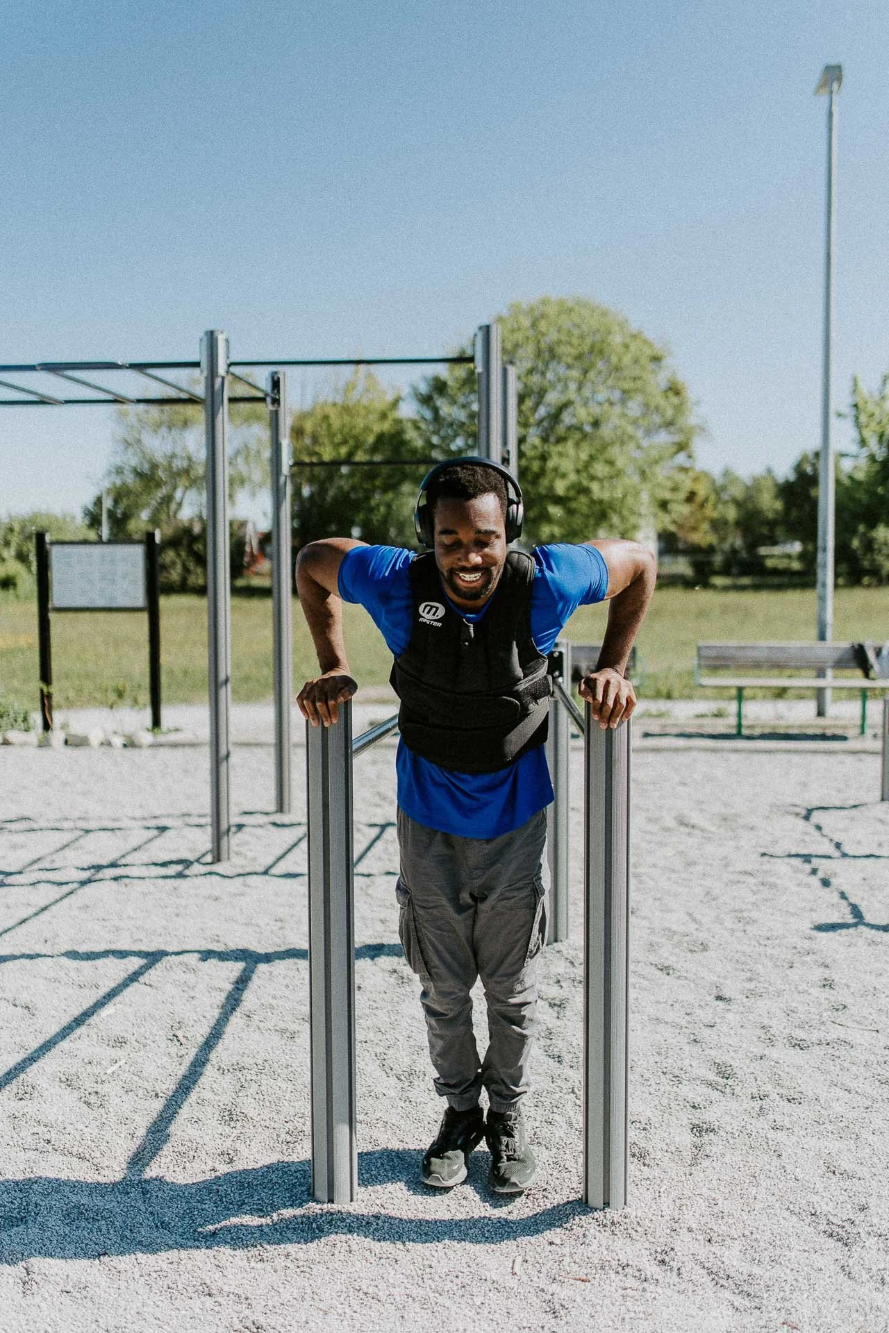Man som trener på utendørs treningsapparat sol han smiler naturlig lys, reklamefotografering for stavanger kommune, områdesatsingen på kvernevik tatt på sommeren