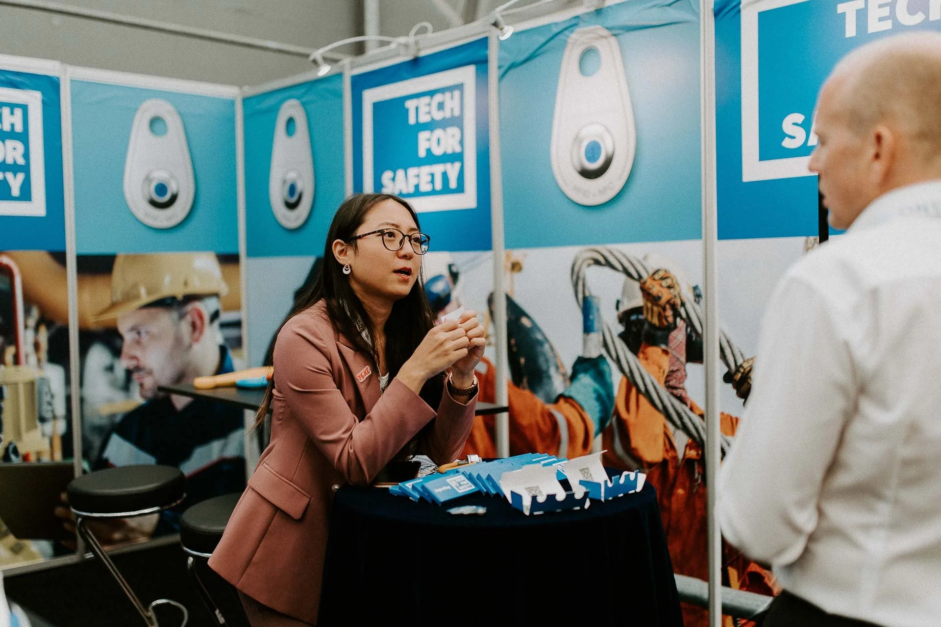 Kvinne som skal selge et produkt engasjert snakker med en mann dokumentarfotografering for ONS, Offshore Northern Seas i Stavanger, stavanger forum mye blått i bakgrunnen 